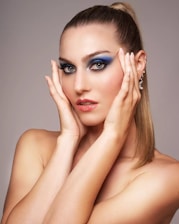 Woman with dramatic blue eyeshadow and hands framing face