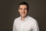 Man in white shirt smiling against a grey background