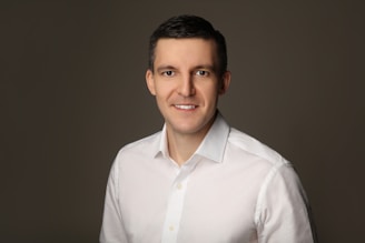 Man in white shirt smiling against a grey background