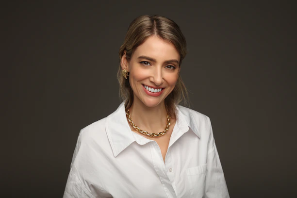A smiling woman wearing a white shirt and necklace