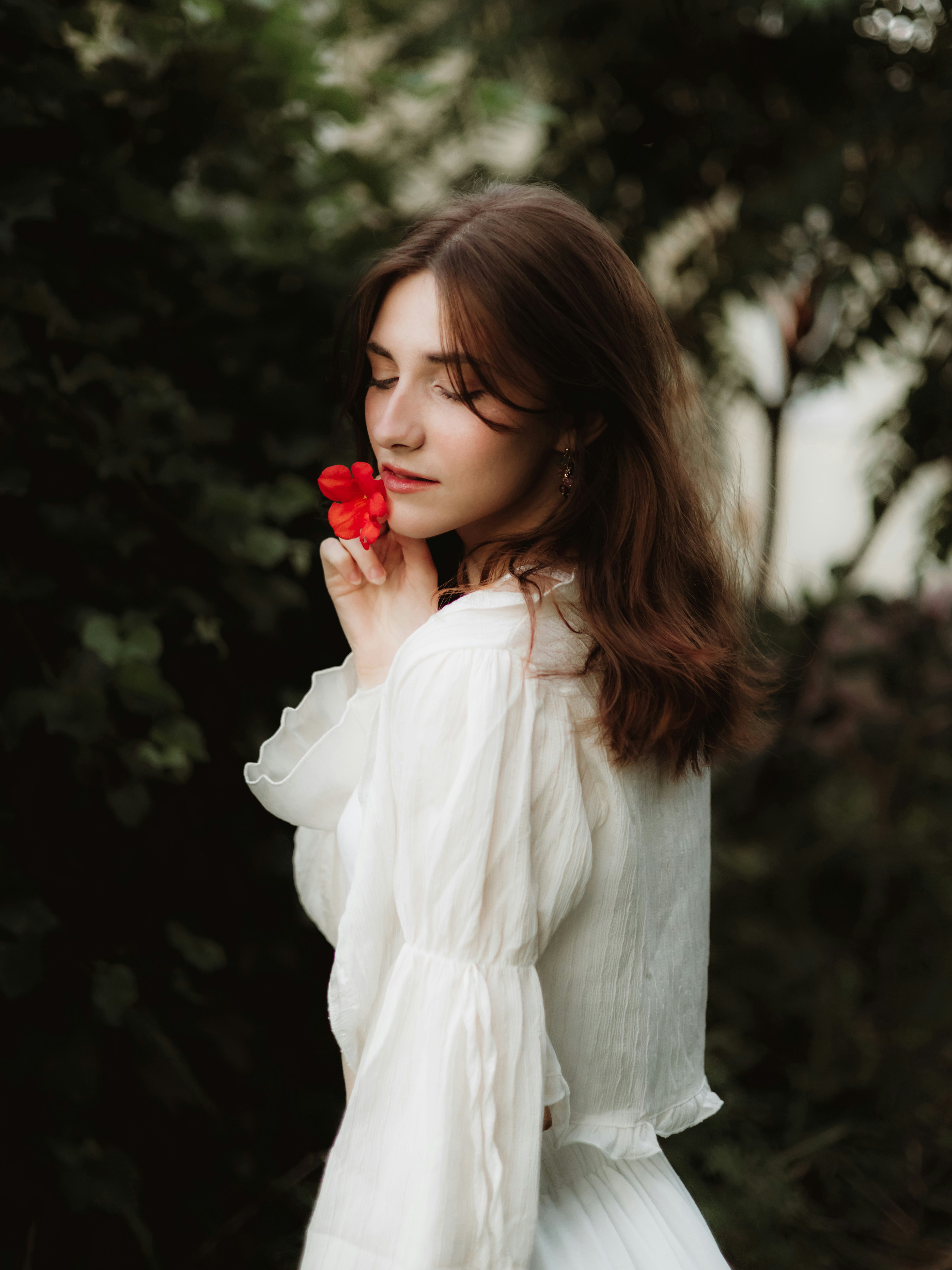 Woman holding a red flower with eyes closed