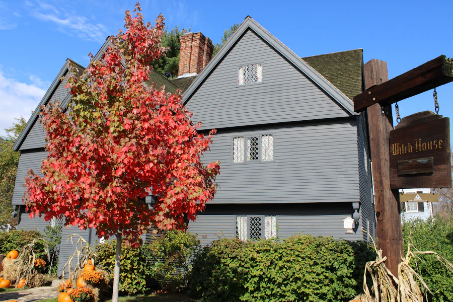 New England gray colonial home framed by red autumn foliage