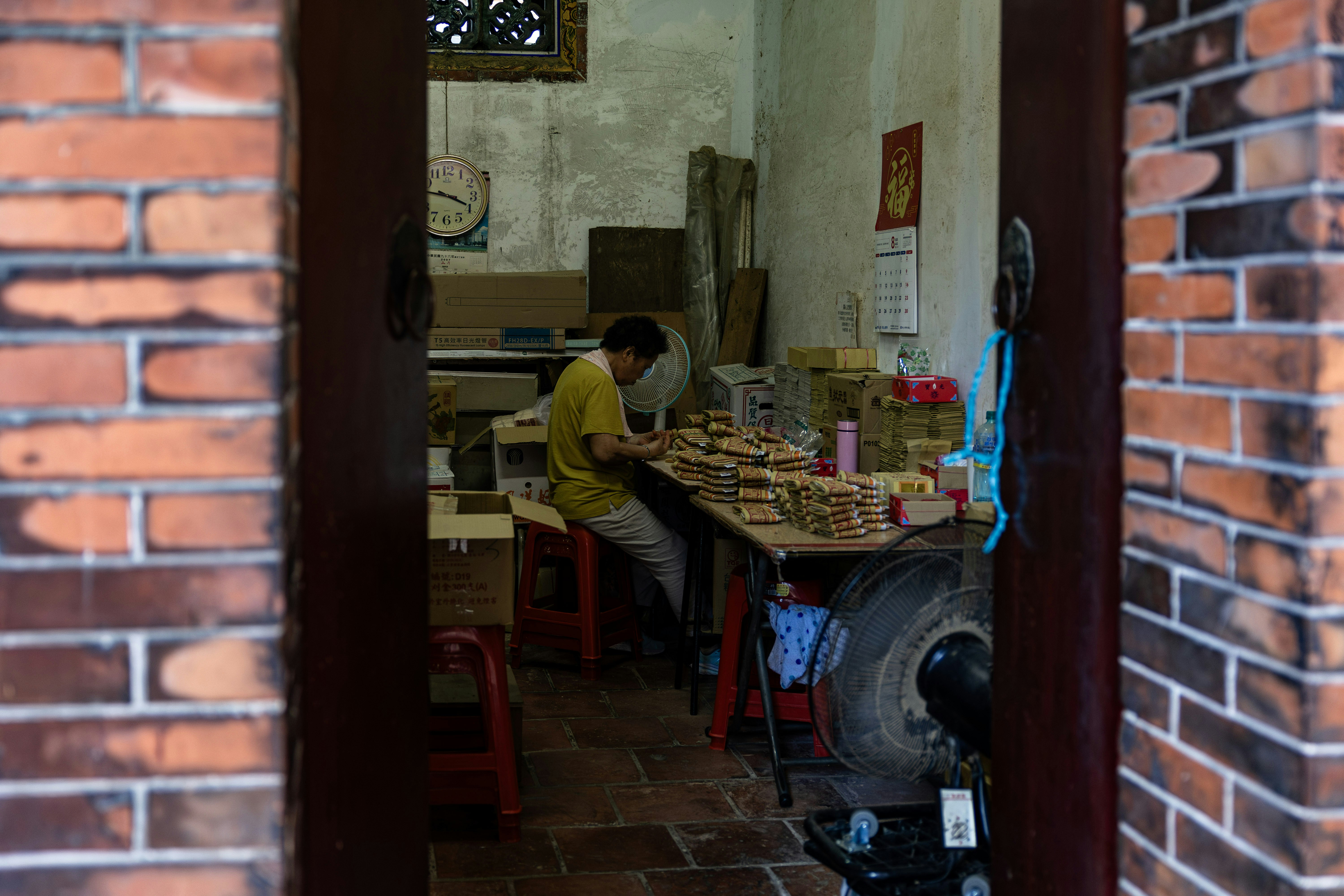 Homem trabalhando em uma mesa de madeira com muitas caixas.