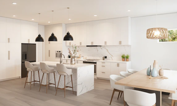 Modern white kitchen with marble island and dining area.