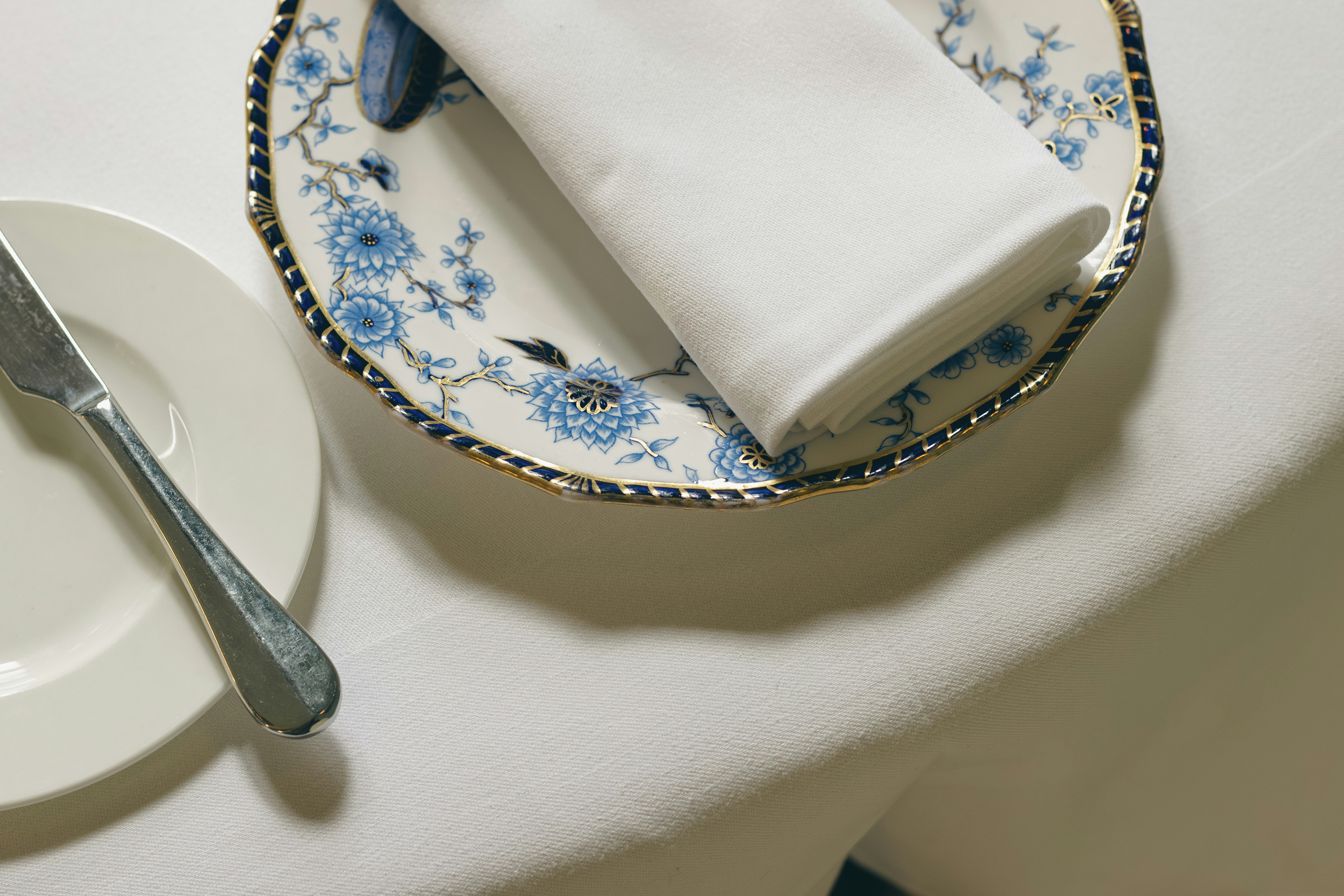 A formal place setting with a floral plate and napkin.