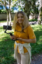Young woman holding a smartphone on a gimbal outdoors.