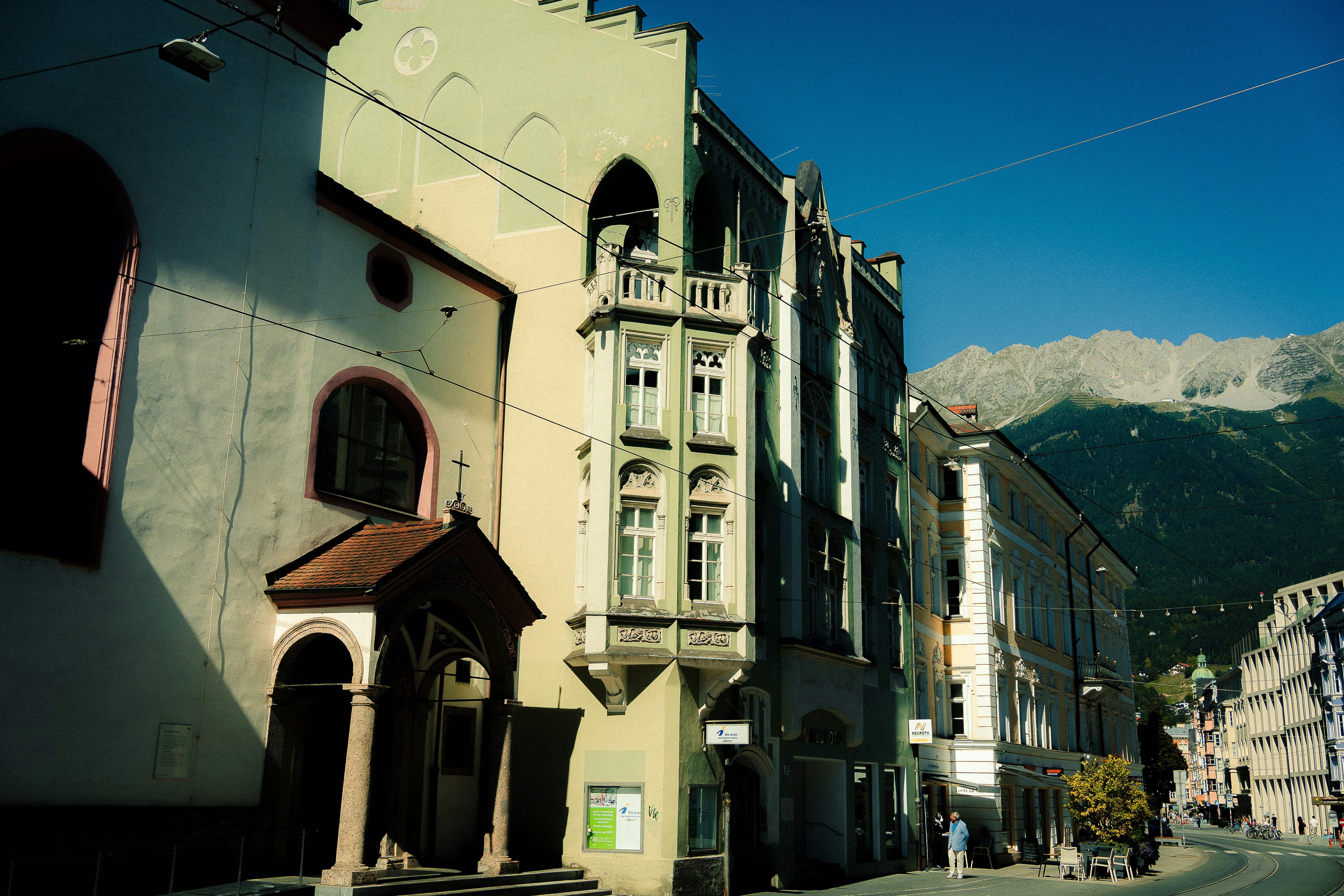 Street view of old european buildings with mountains behind.