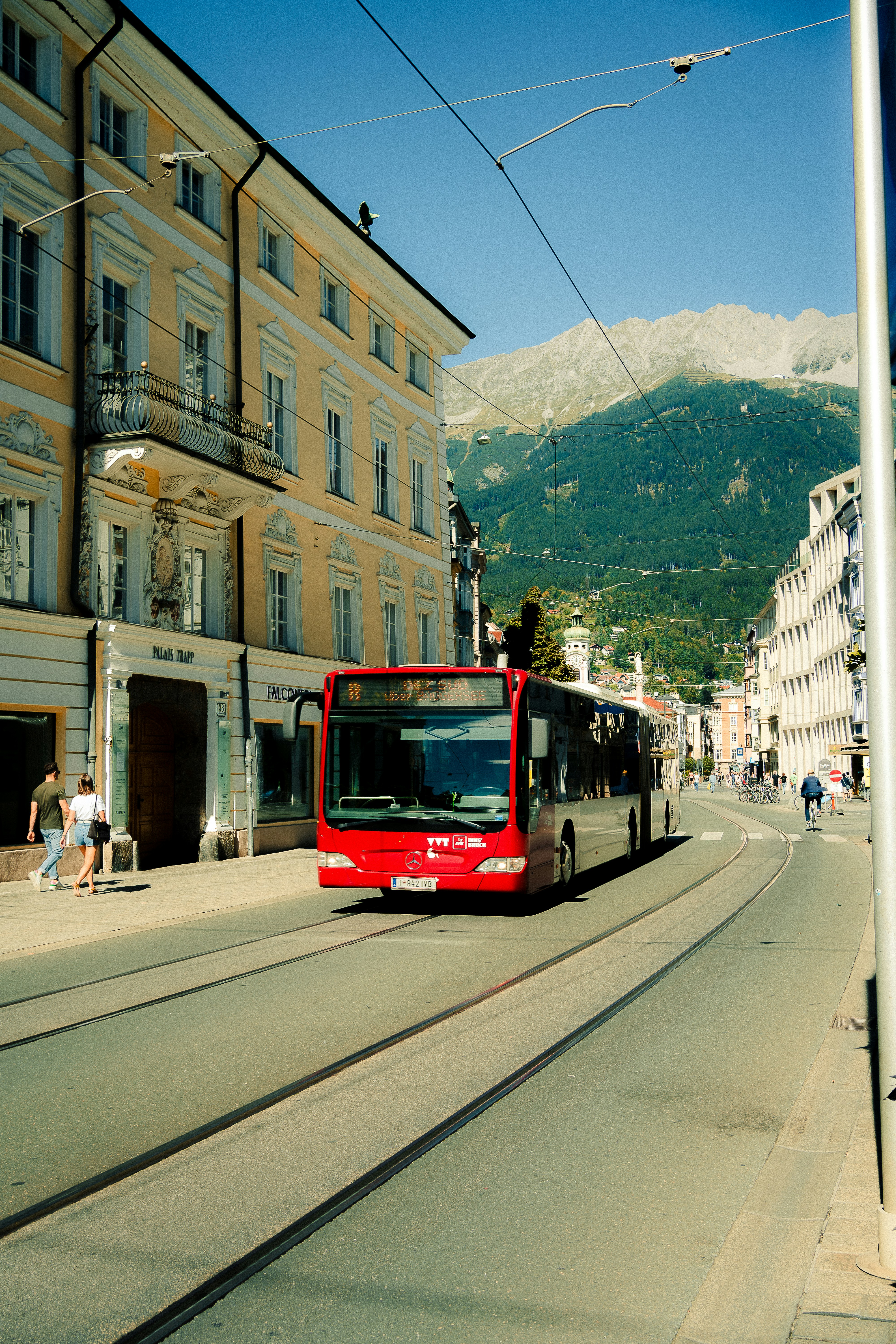 Red bus driving down a city street with mountains.