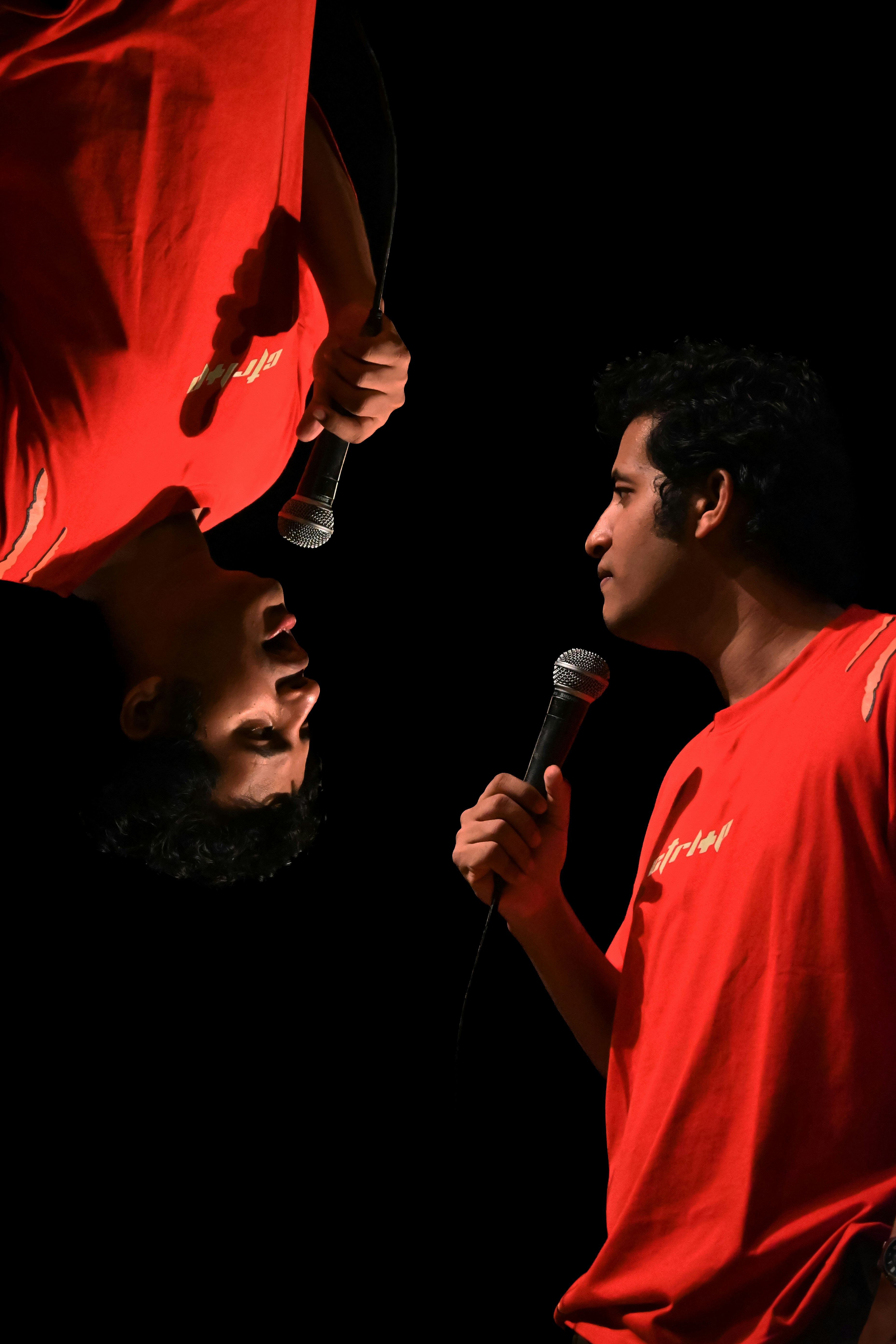 Man in red shirt holding microphone, upside down reflection.