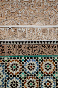 Intricate geometric tile and stucco patterns on a wall.