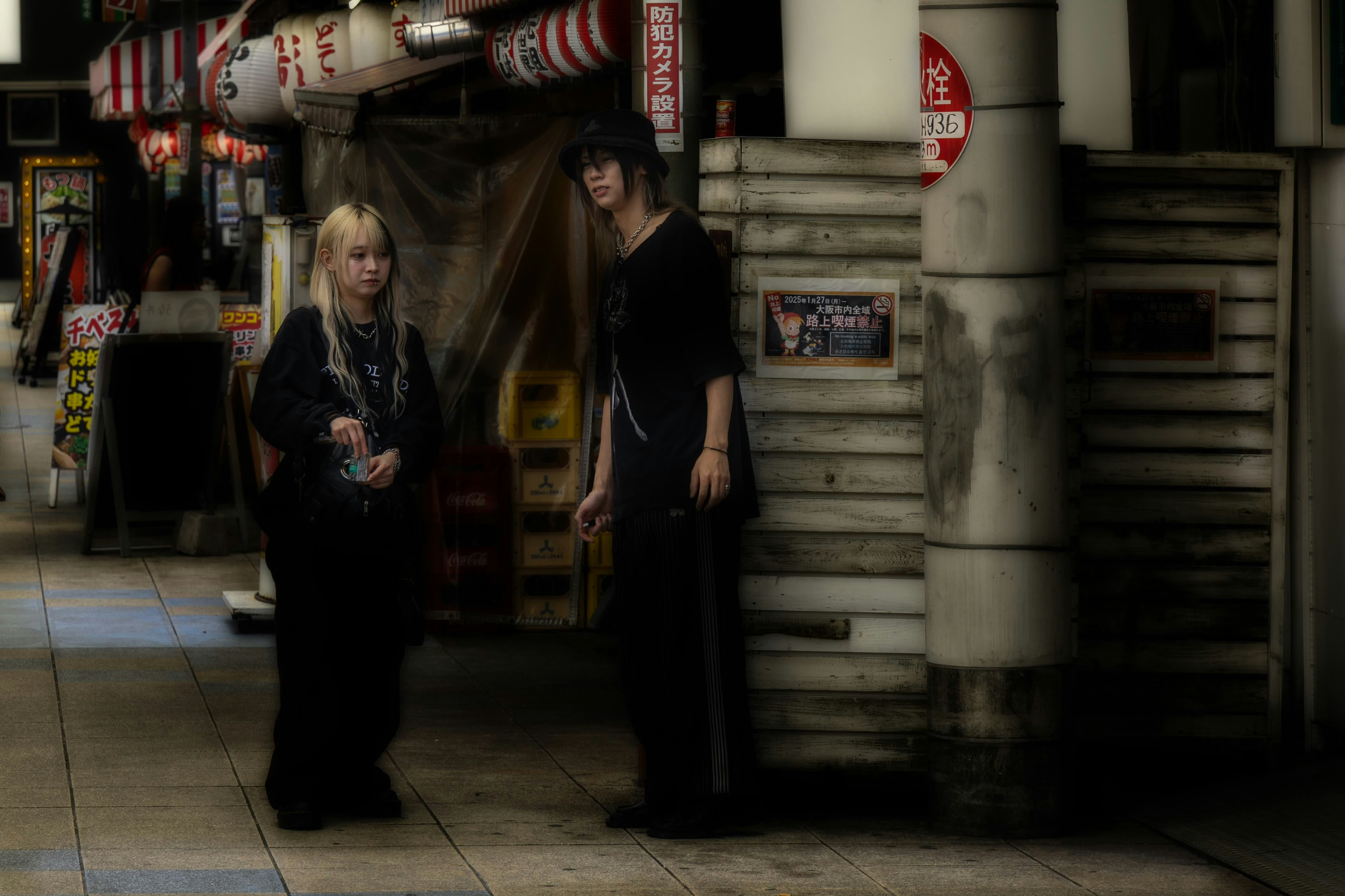 Two people stand on a street at night.