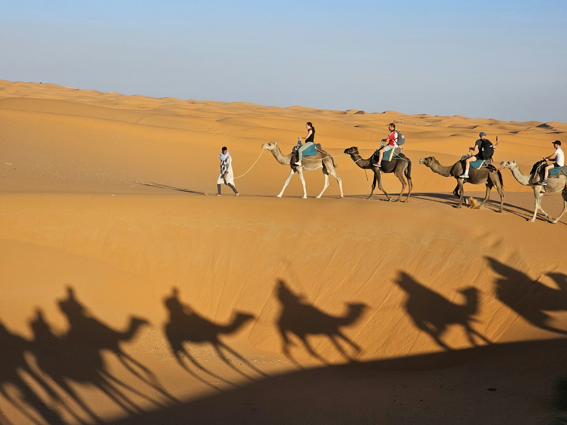 People riding camels in a desert landscape