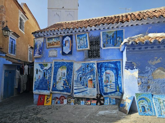 Blue building with artwork displayed outside — Chefchaouen, Morocco