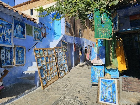 Blue buildings with art displayed on street — Chefchaouen, Morocco