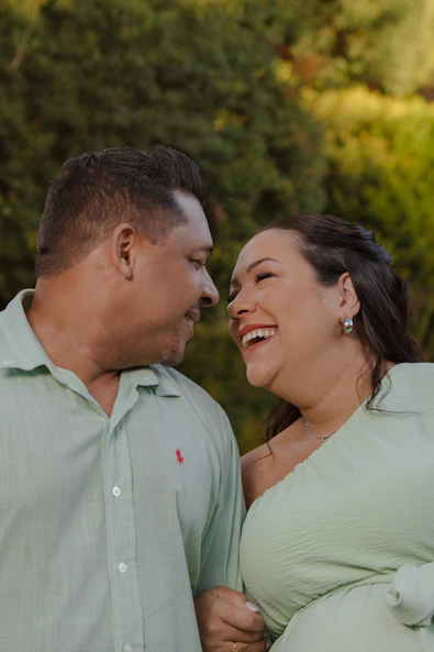 Couple laughing together outdoors with trees in background