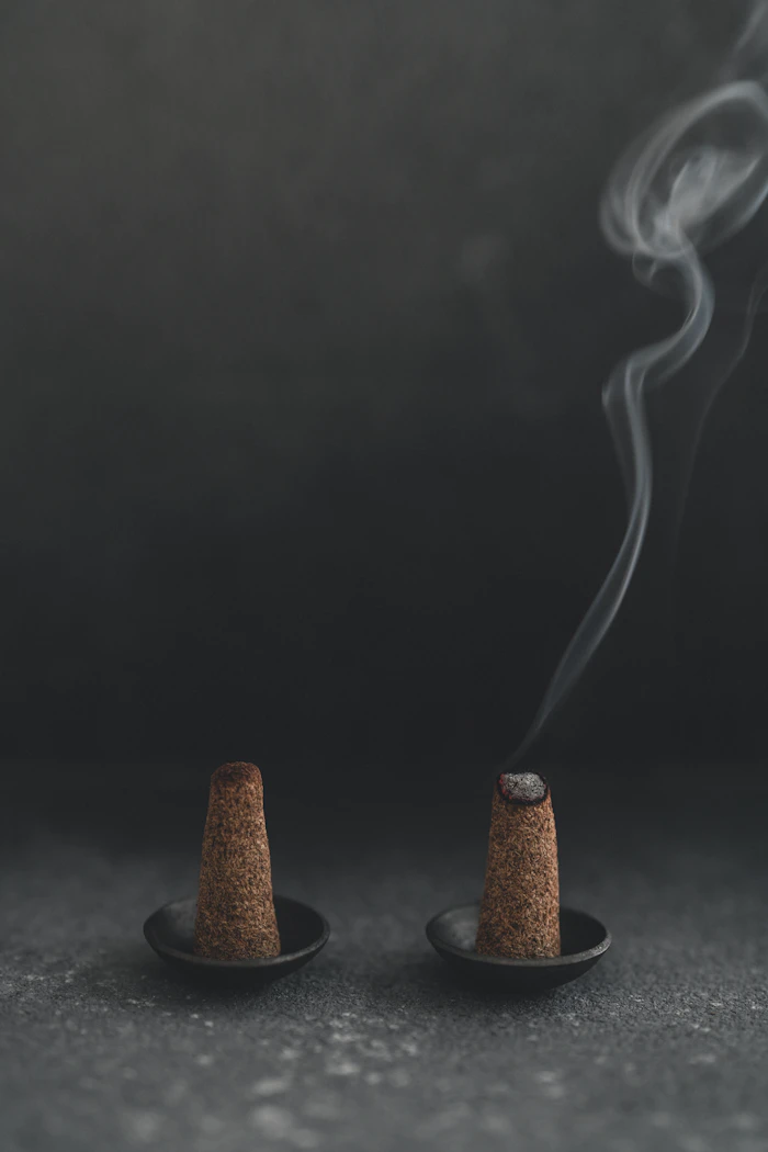 Incense cones smoldering, sending up a thin ribbon of smoke