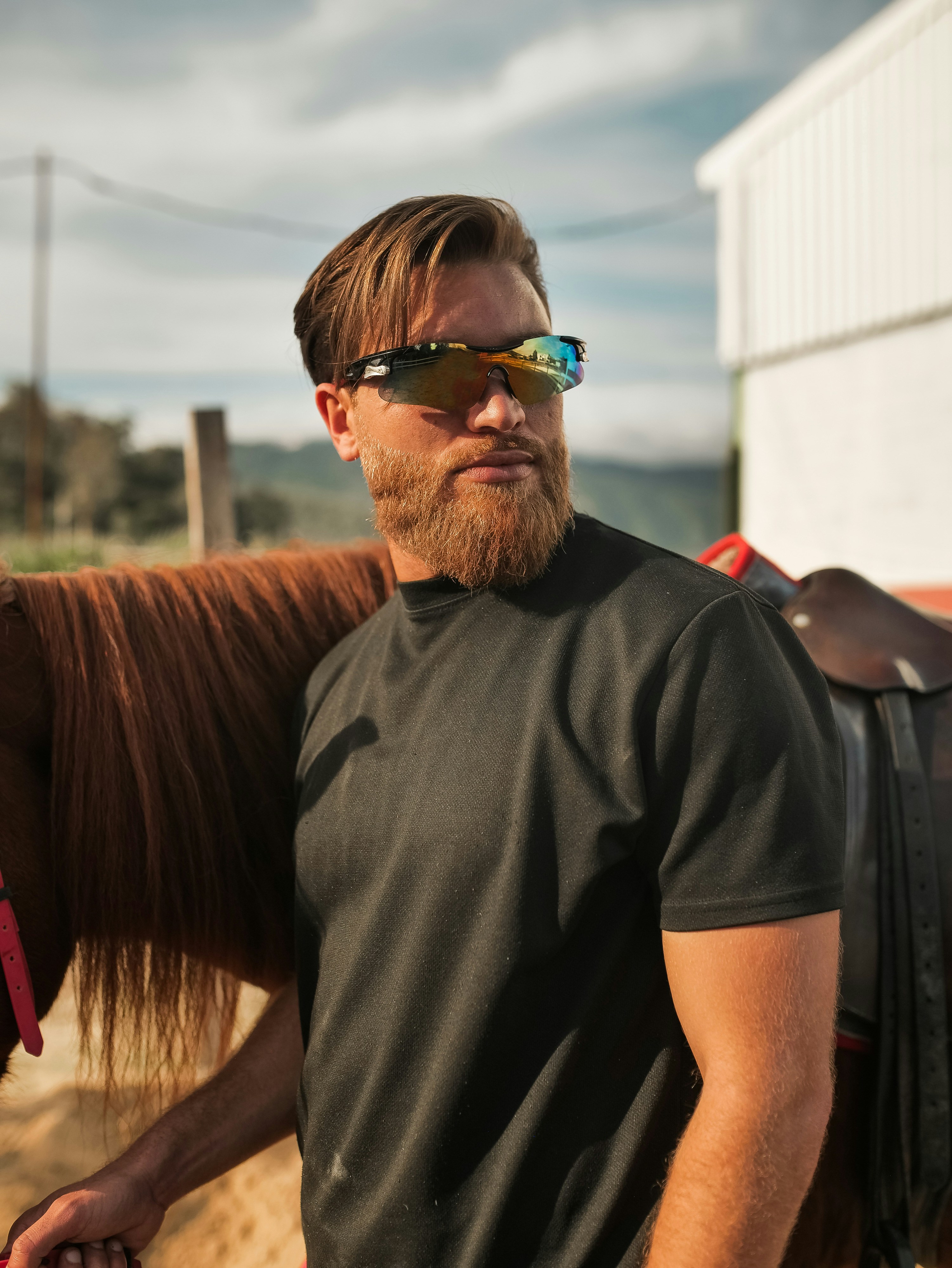 Man with beard and sunglasses next to horse