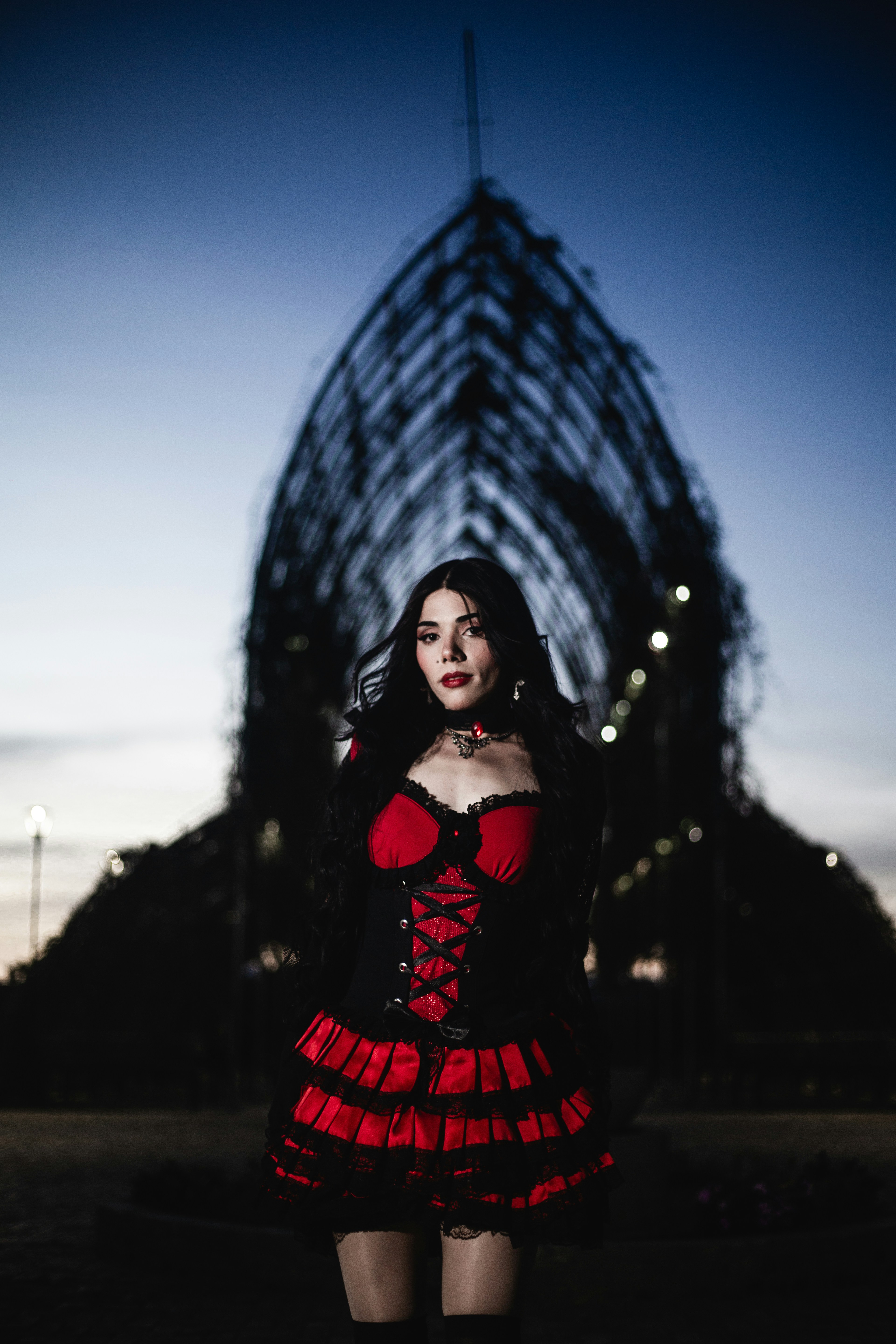 Woman in a red and black gothic dress at dusk