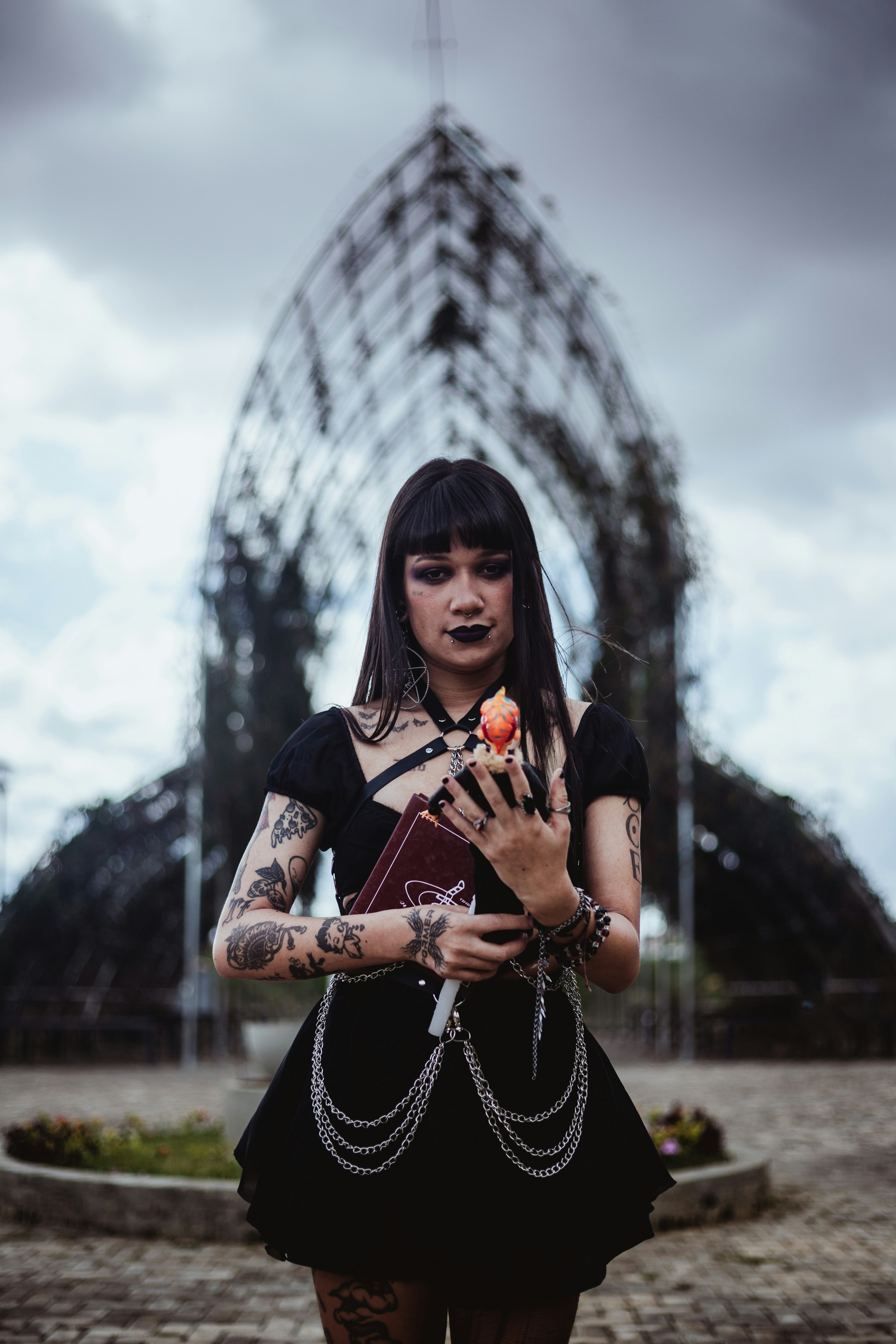 Goth woman holding a peach in front of arched structure