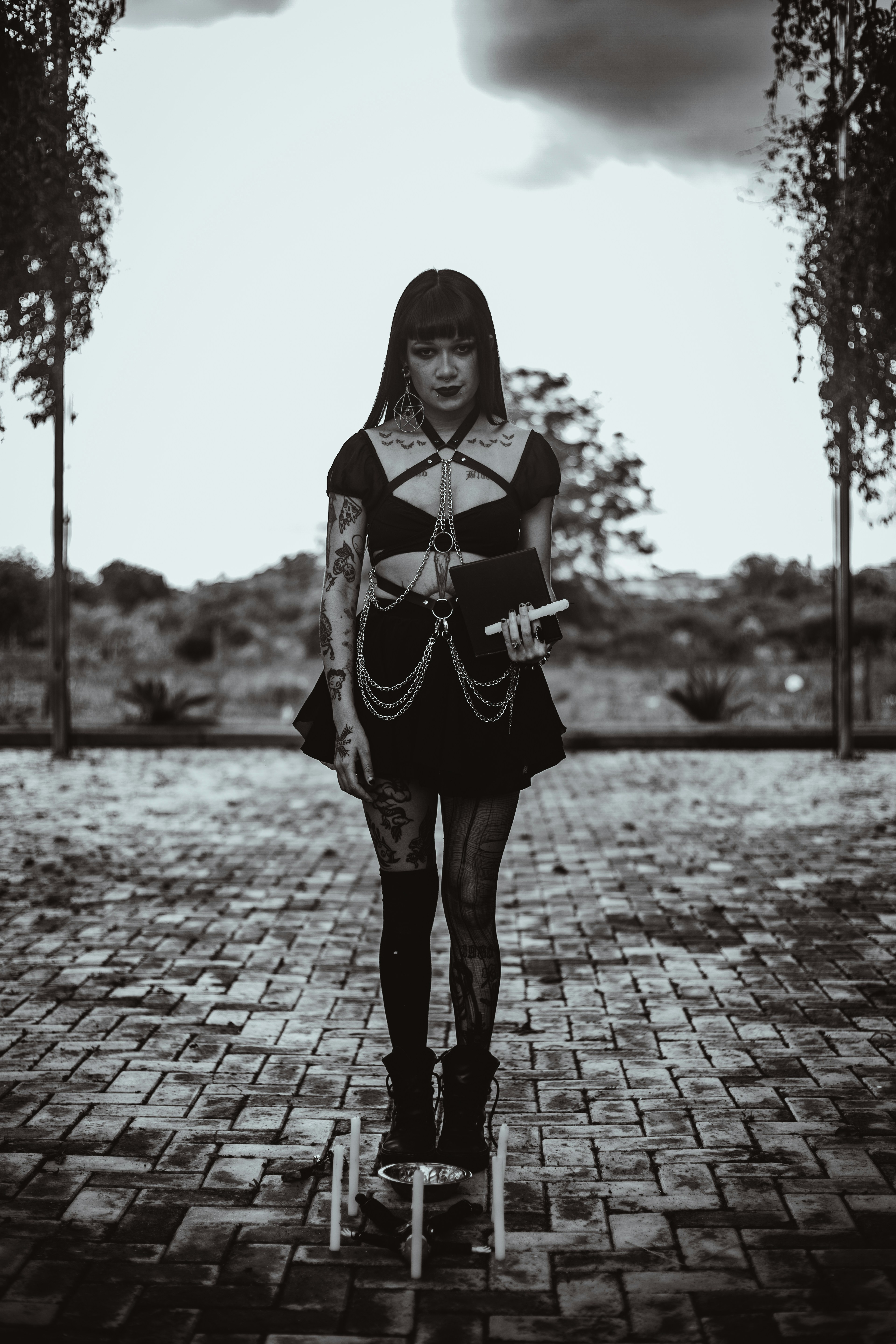 Mulher com tatuagens segurando um livro e velas