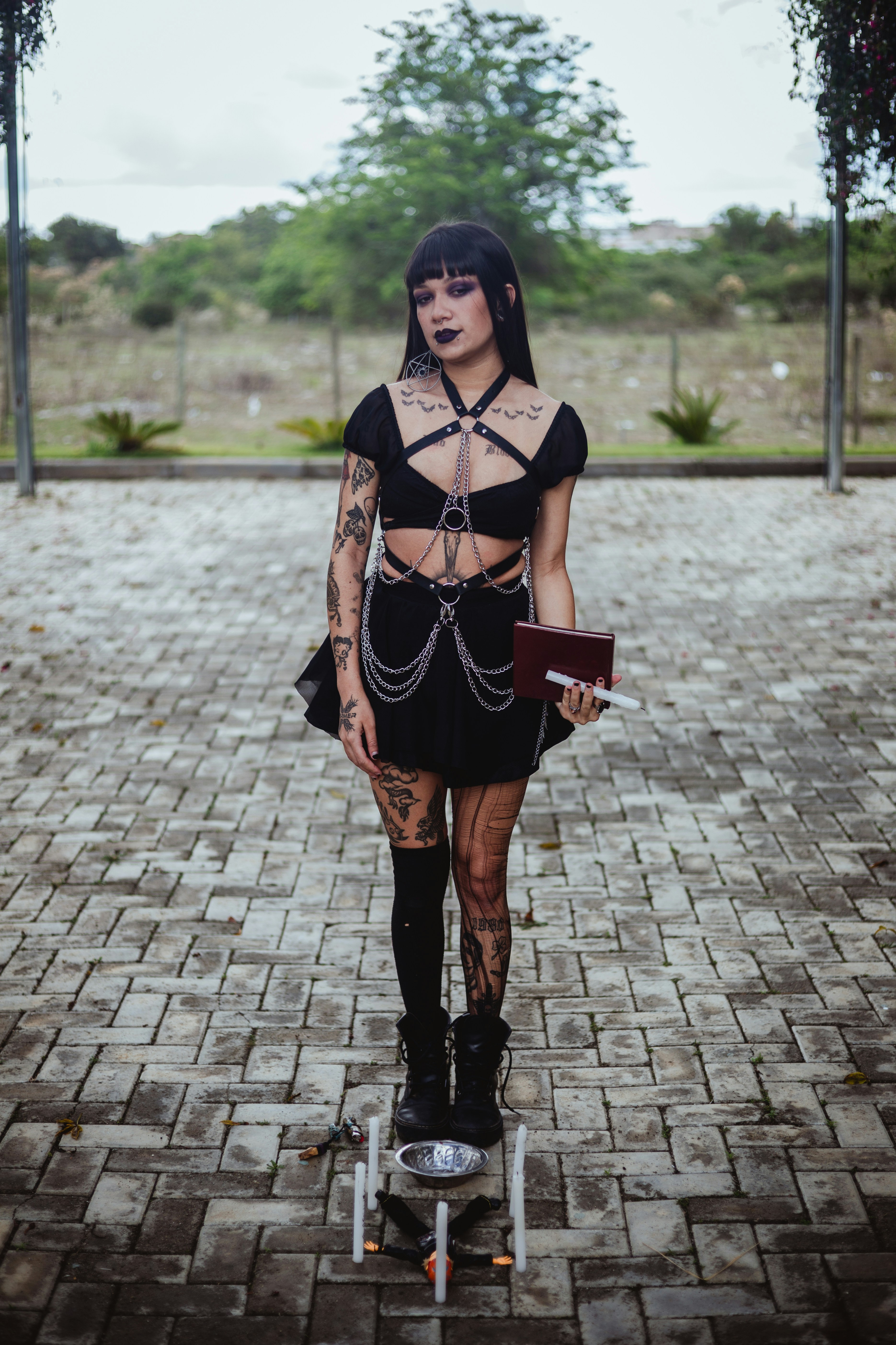 Woman in gothic attire holding a book outdoors.