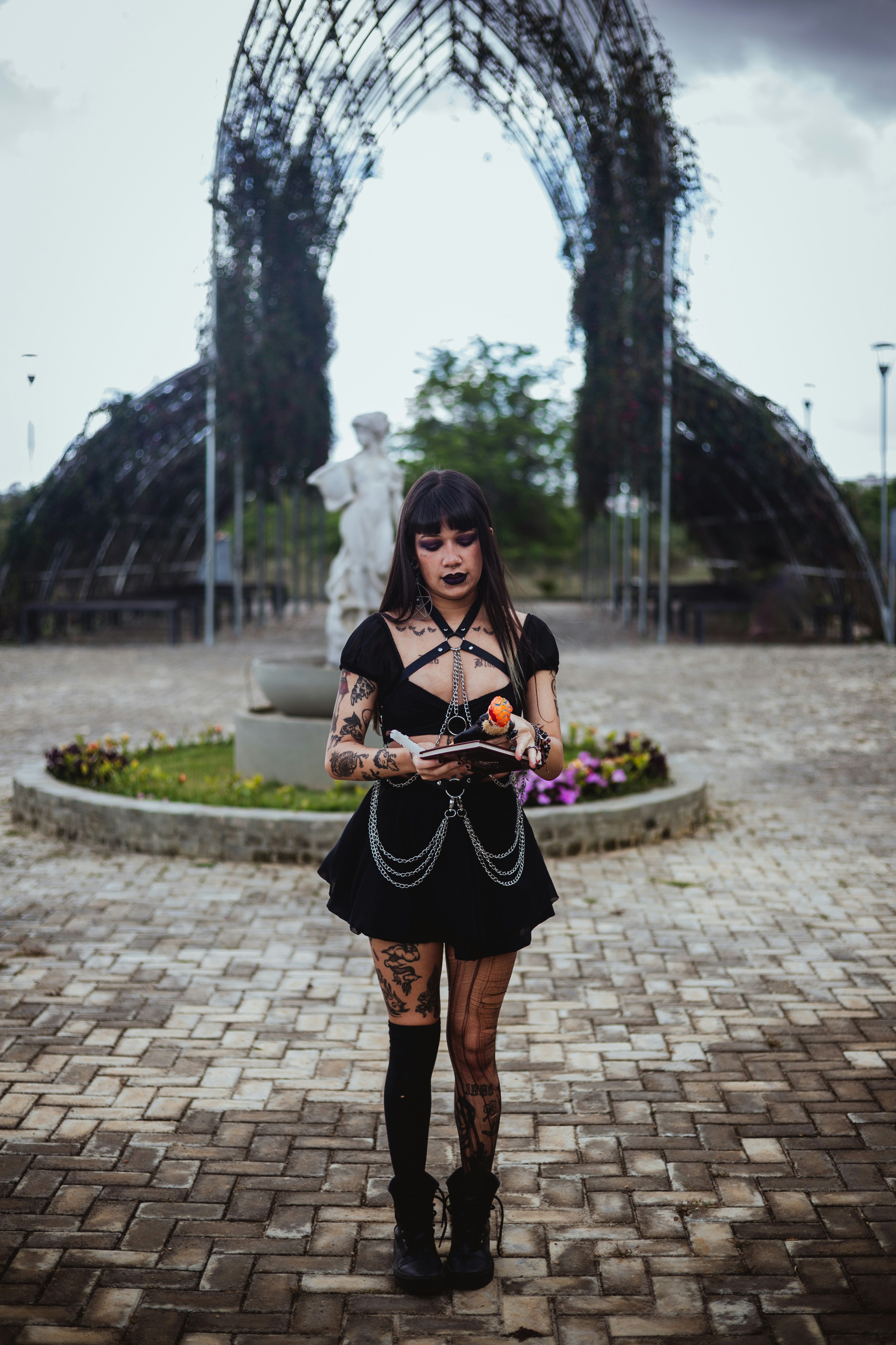 Goth woman with tattoos holding a small book.