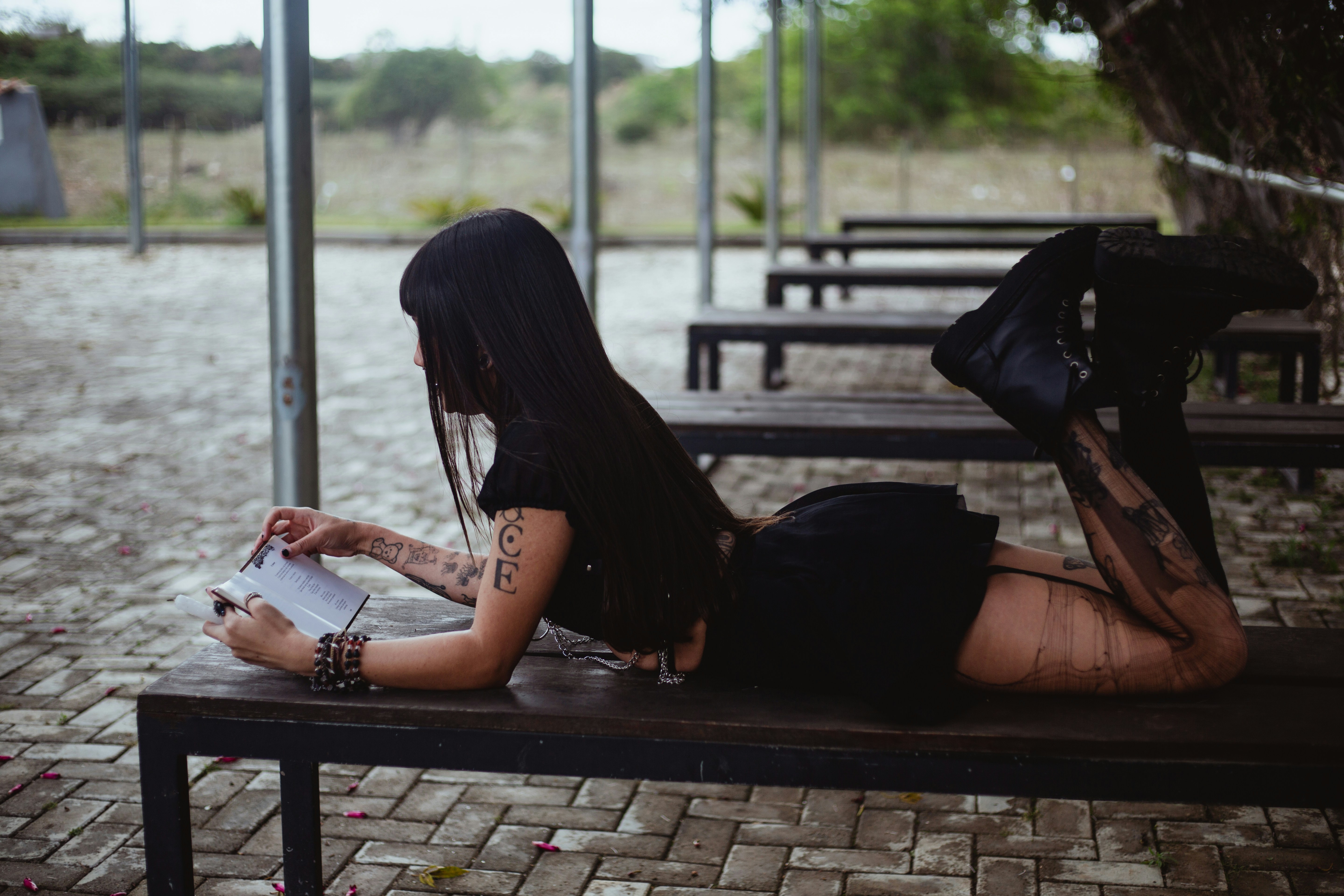Woman in black dress reading a book on a bench
