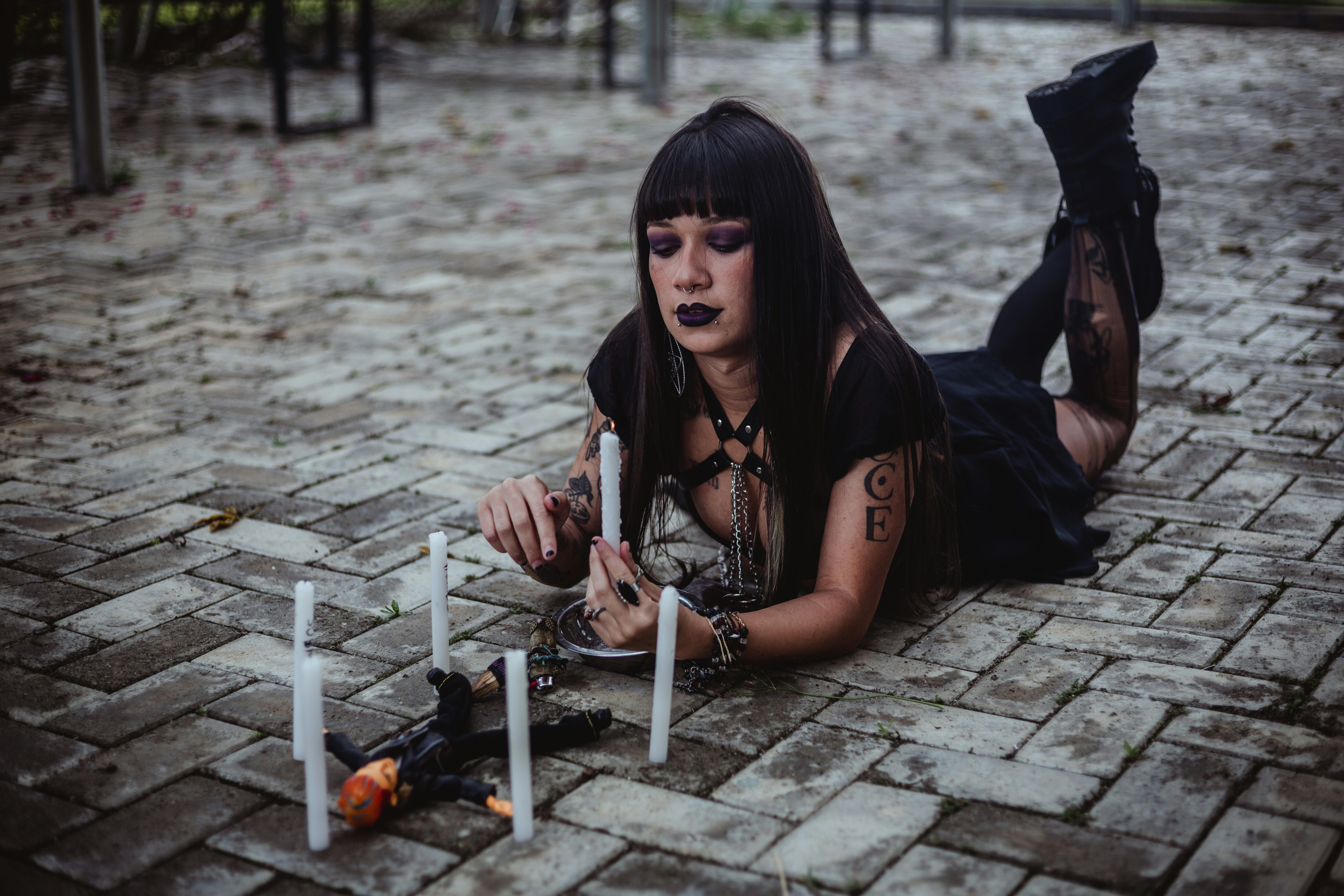 Woman lighting candles around a doll on brick ground