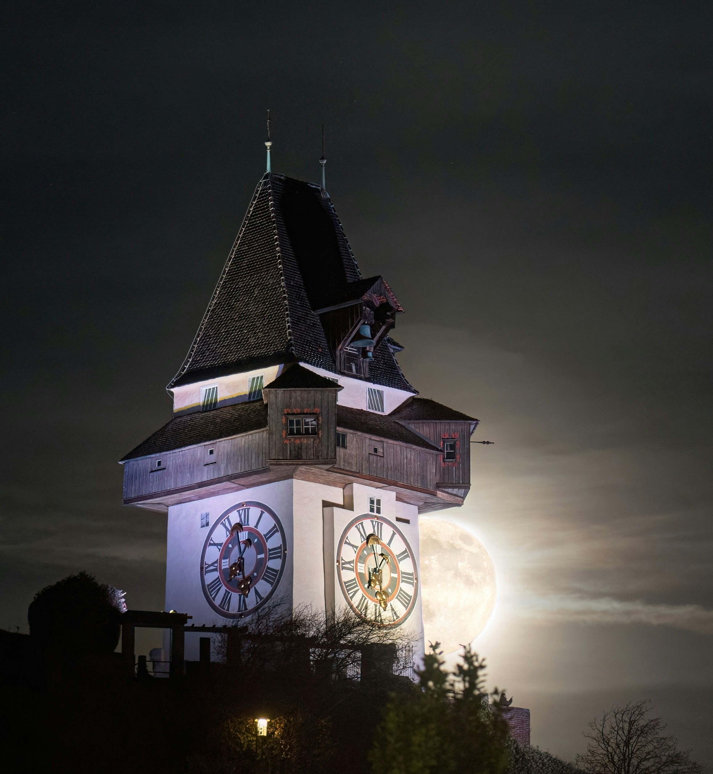 Clock tower illuminated at night with full moon.