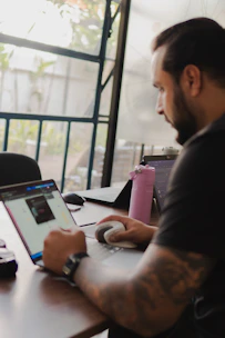 Man working on laptop with pink water bottle nearby