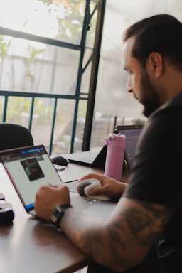 Man working on laptop with pink water bottle nearby