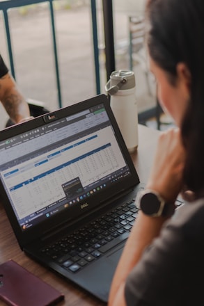 Woman working on a laptop with spreadsheet data.