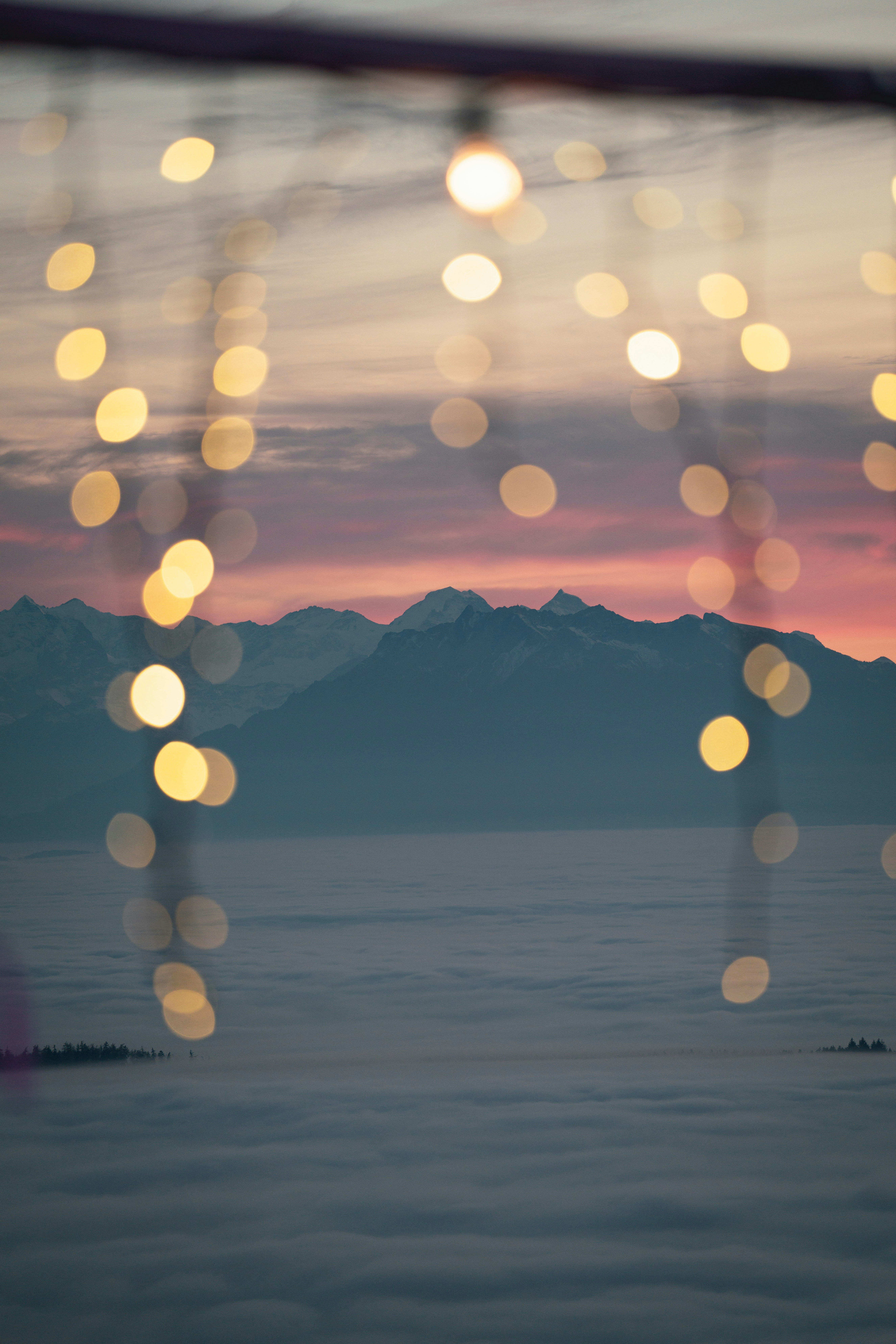 Bokeh lights over misty mountains at sunset