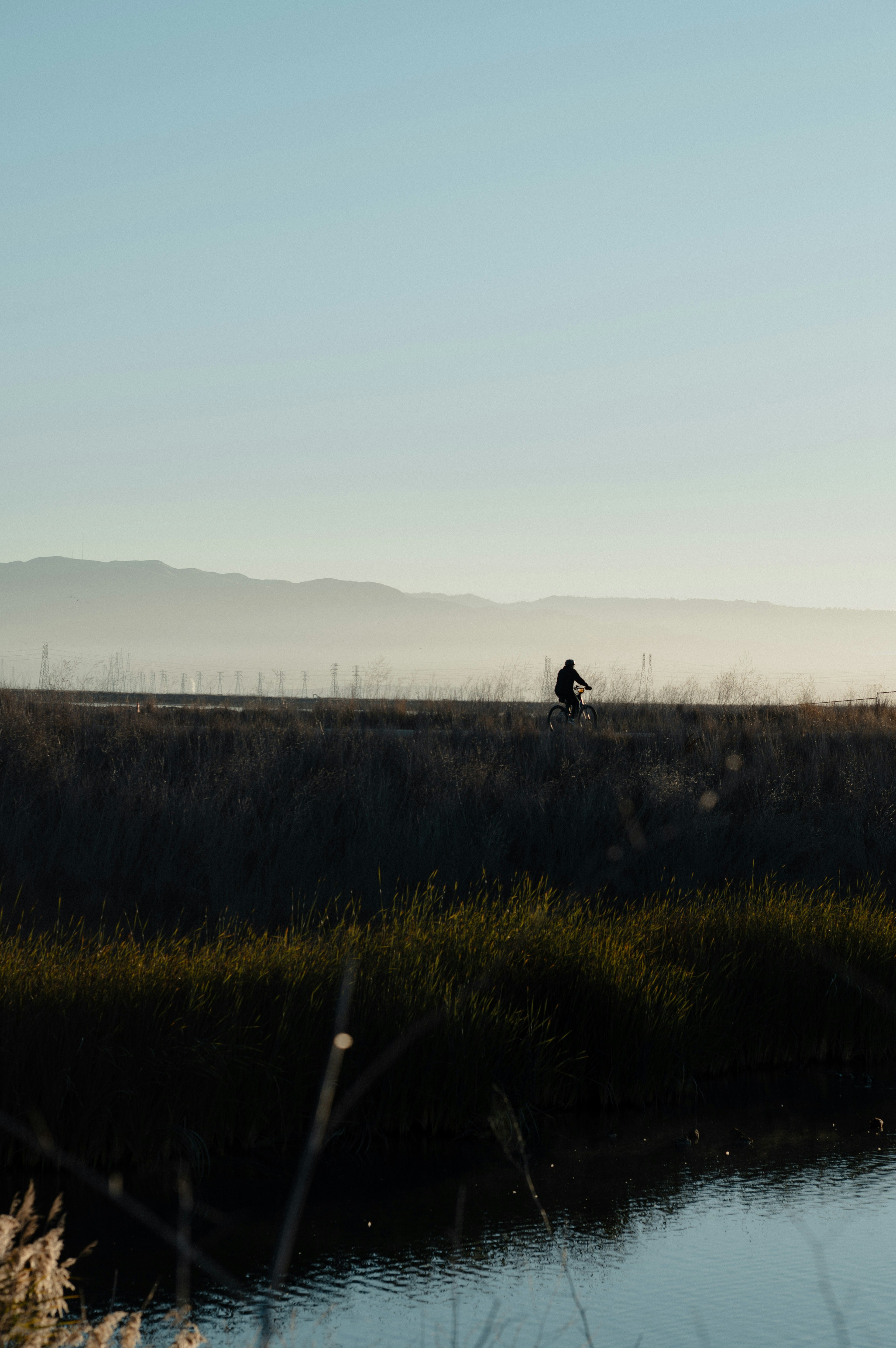 Person cycling on a path with mountains in background.