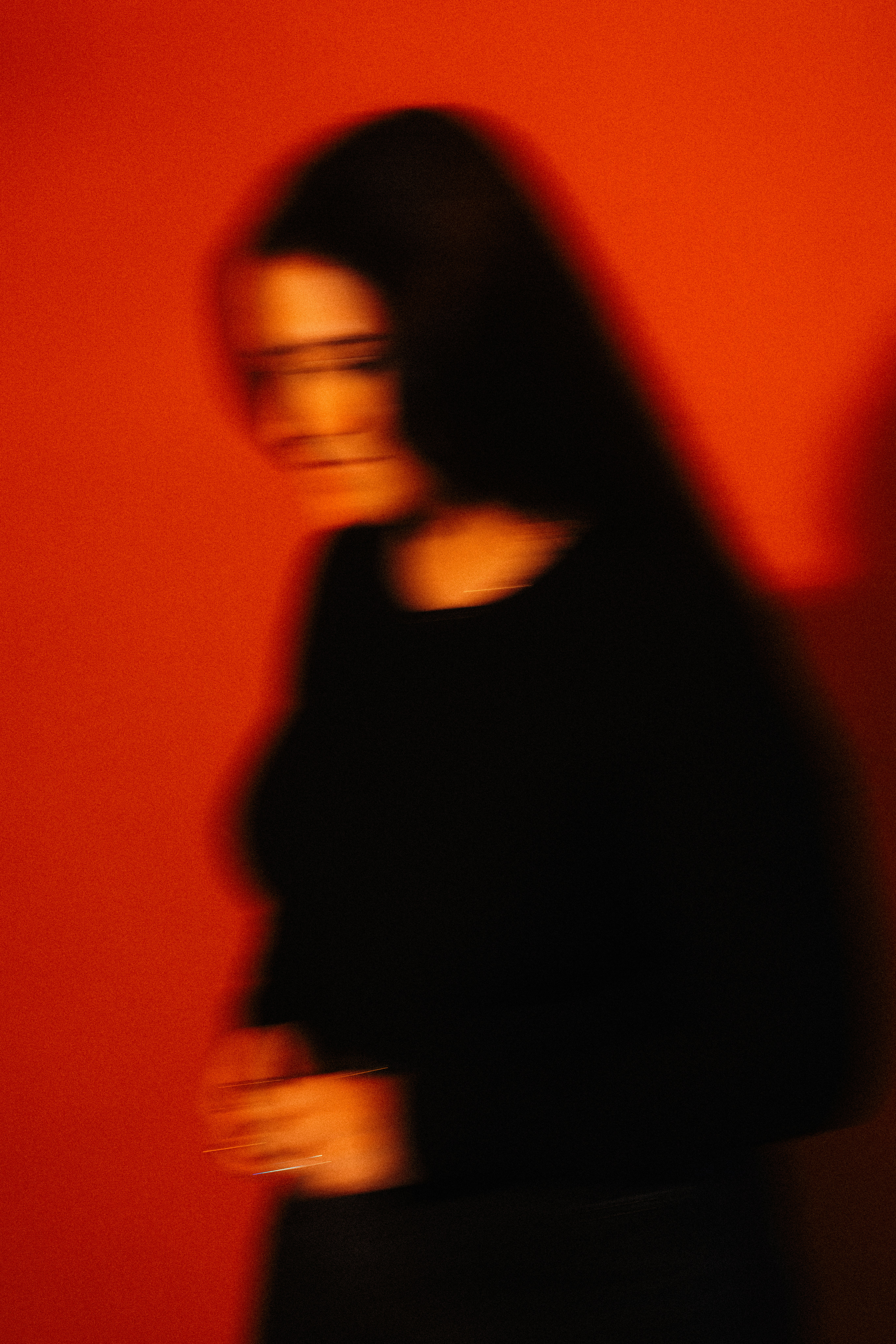Blurred woman in black against red wall