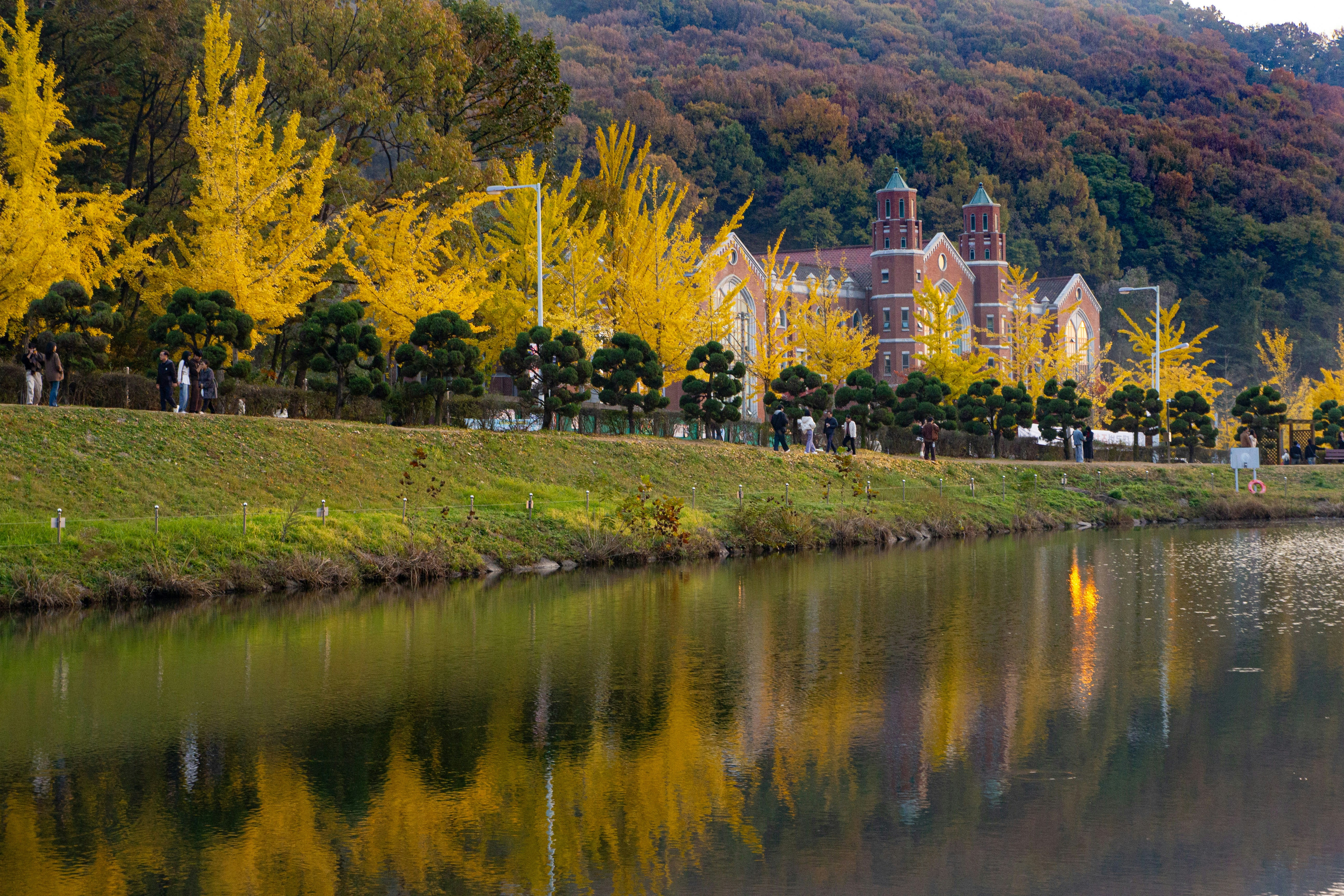 Golden trees line a calm lake with a building.