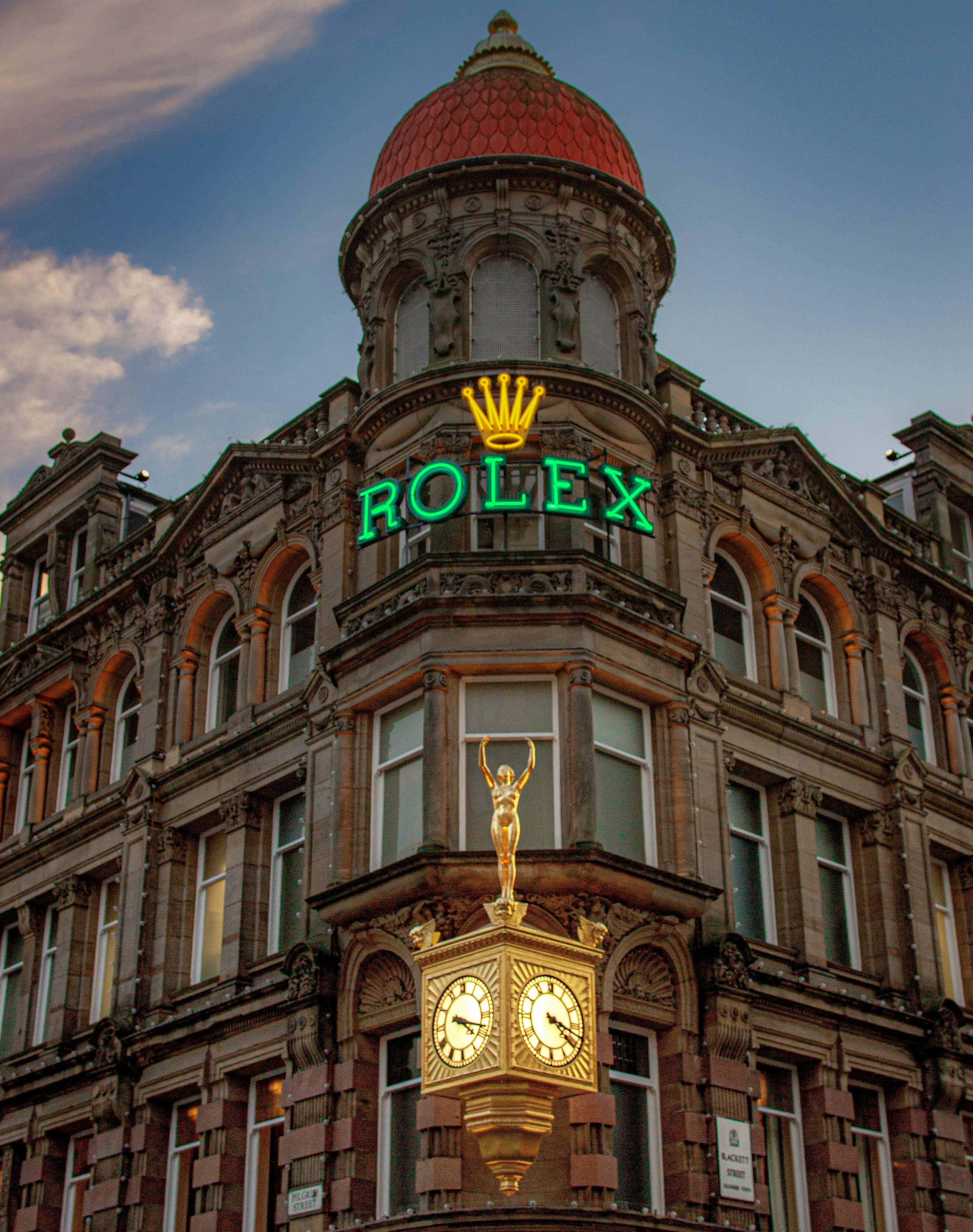 Historic building with rolex sign and ornate clock.