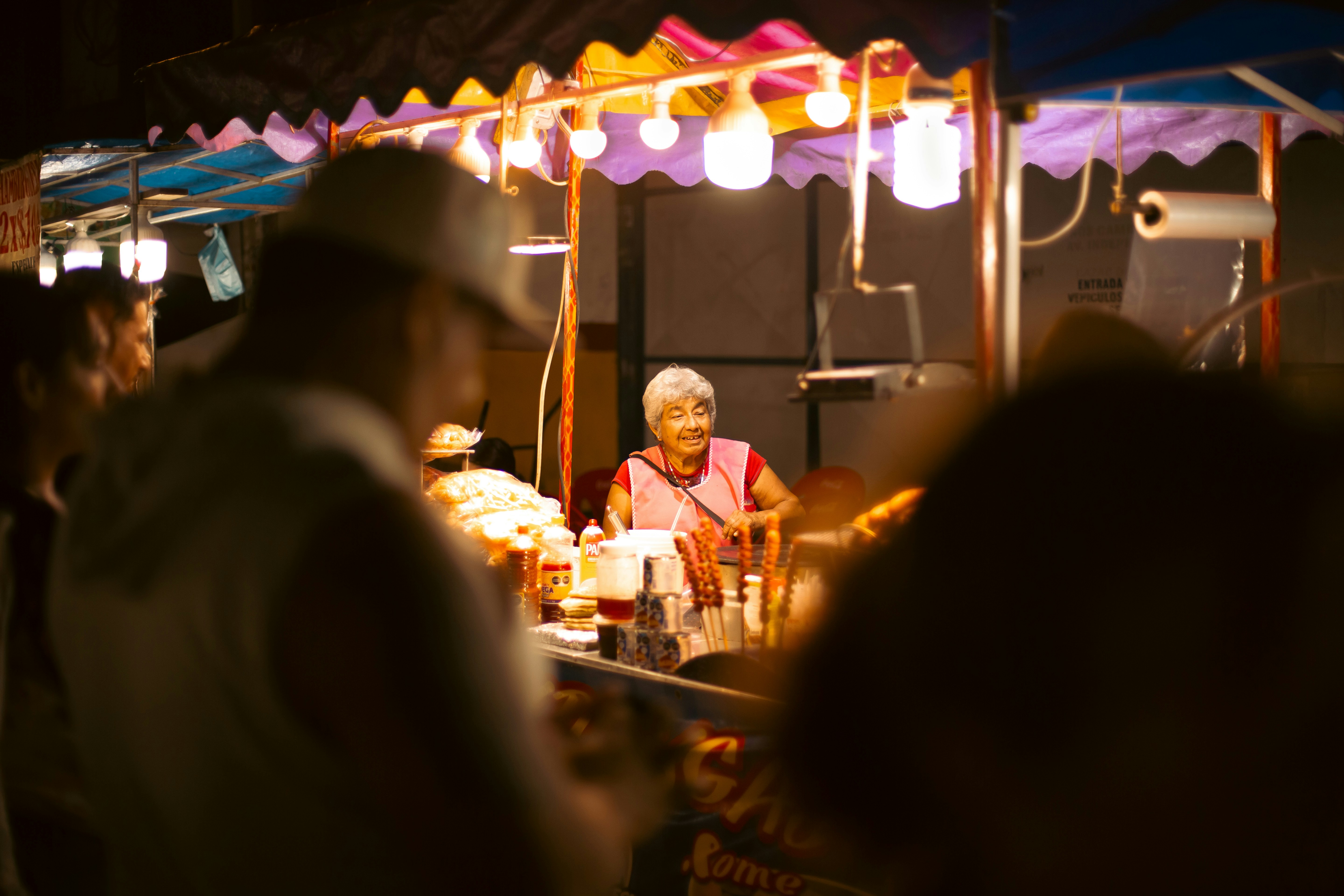 Elderly woman at a brightly lit night market stall