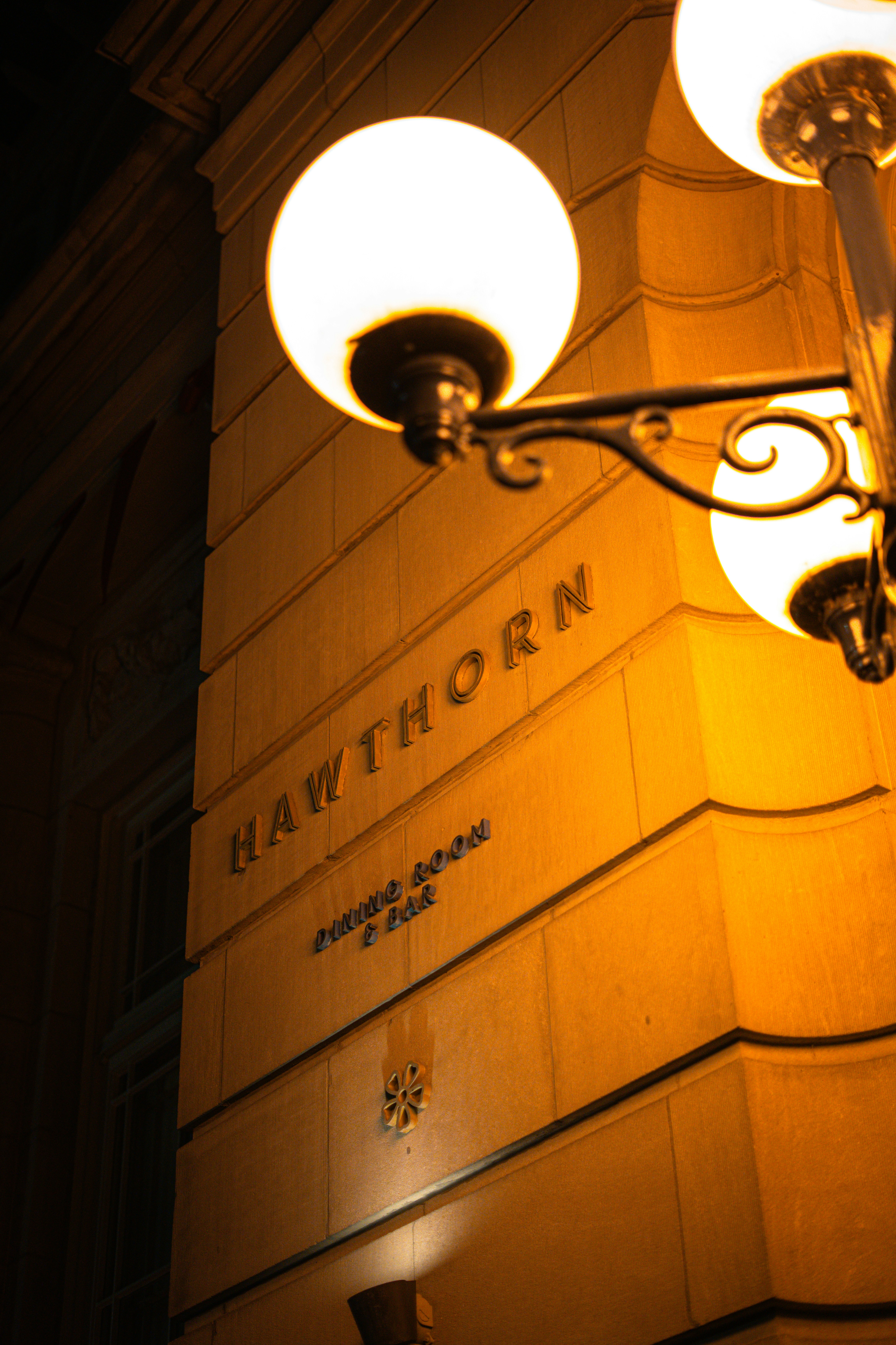 Building exterior at night with ornate street lamps.