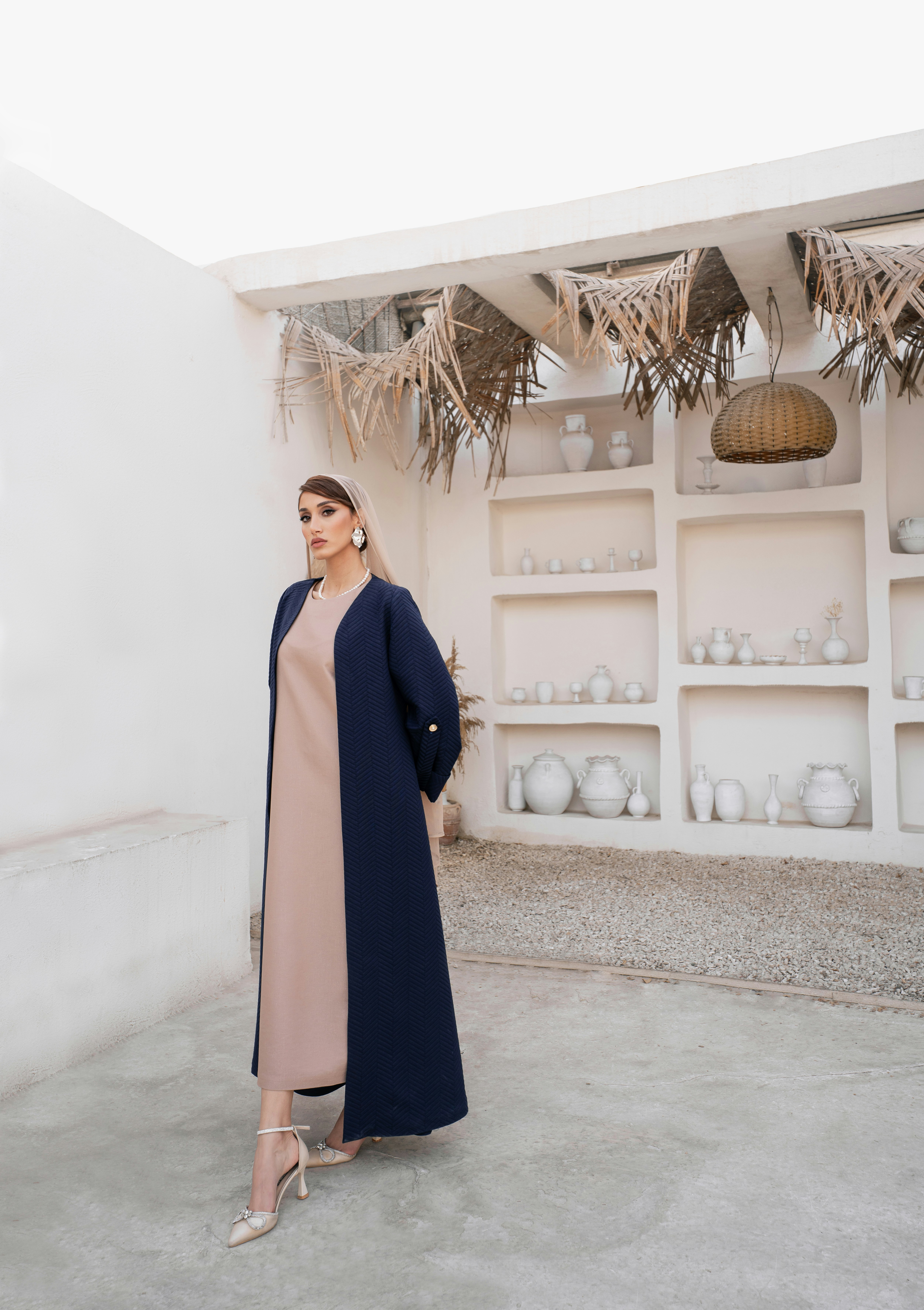 Woman in a beige dress and navy blue abaya.