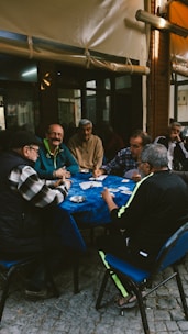 Men playing cards at a table outdoors.