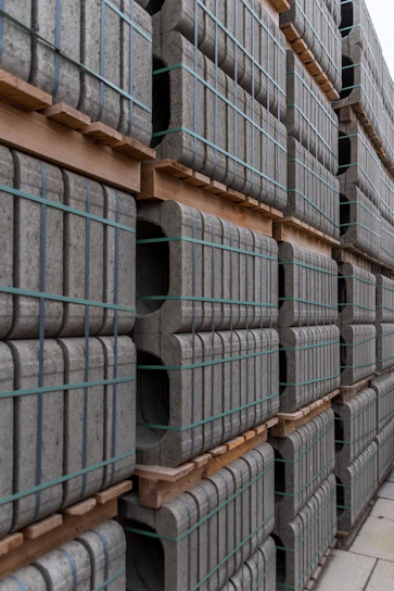 Stacks of gray concrete curbs on wooden pallets