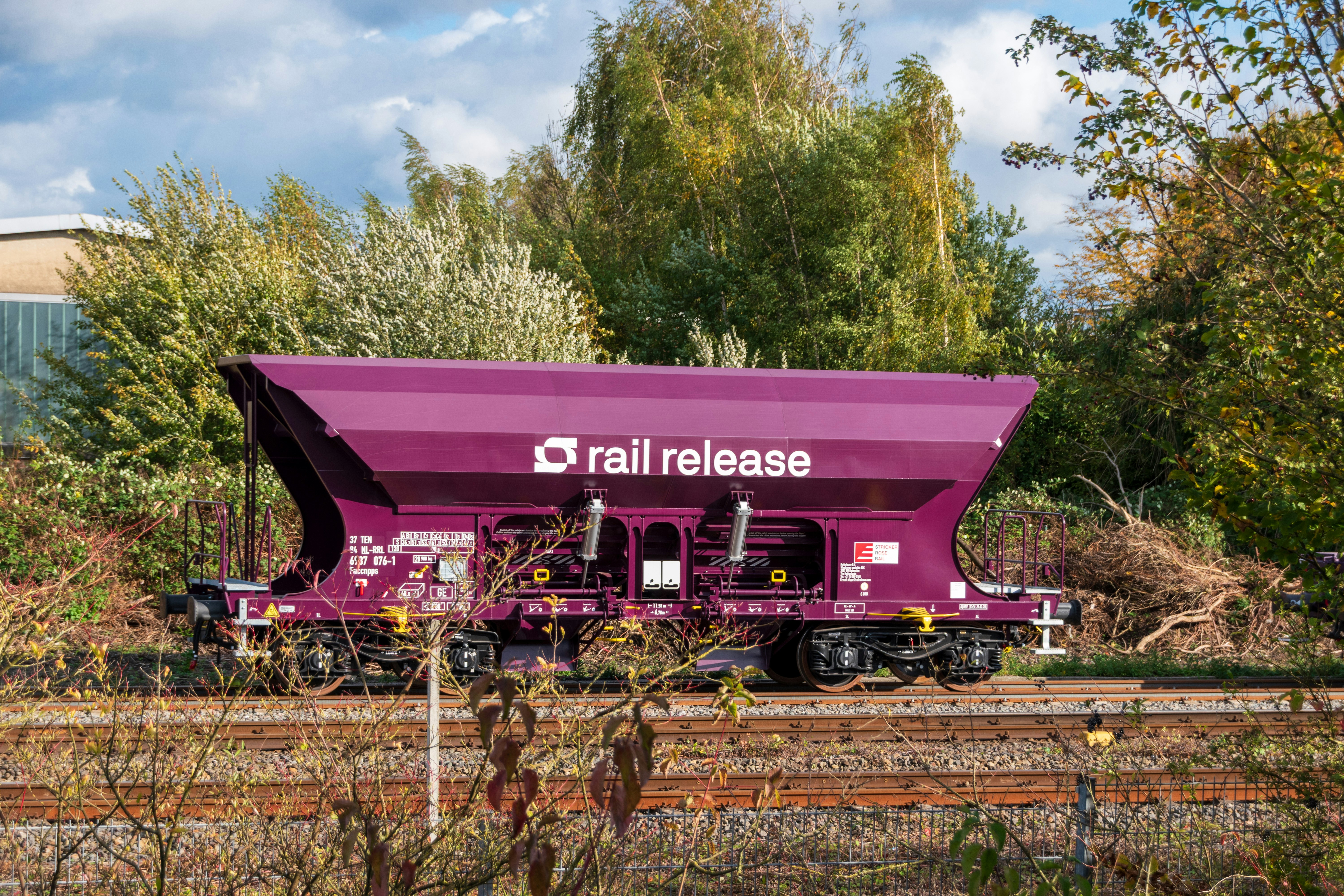 Lila Schüttgutwagen mit "Rail Release"-Logo auf den Gleisen.