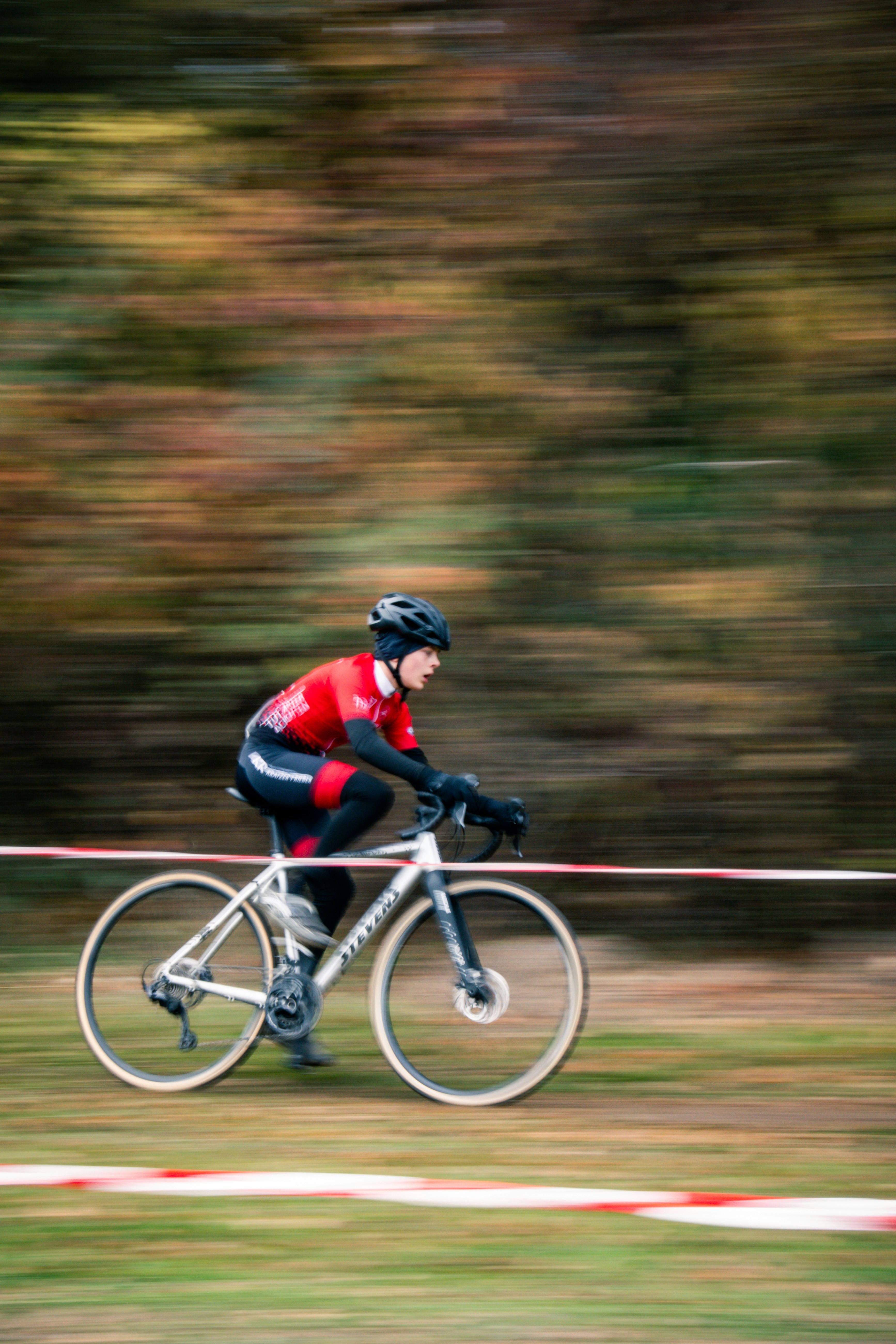 Cyclist in red racing through a blurred forest background