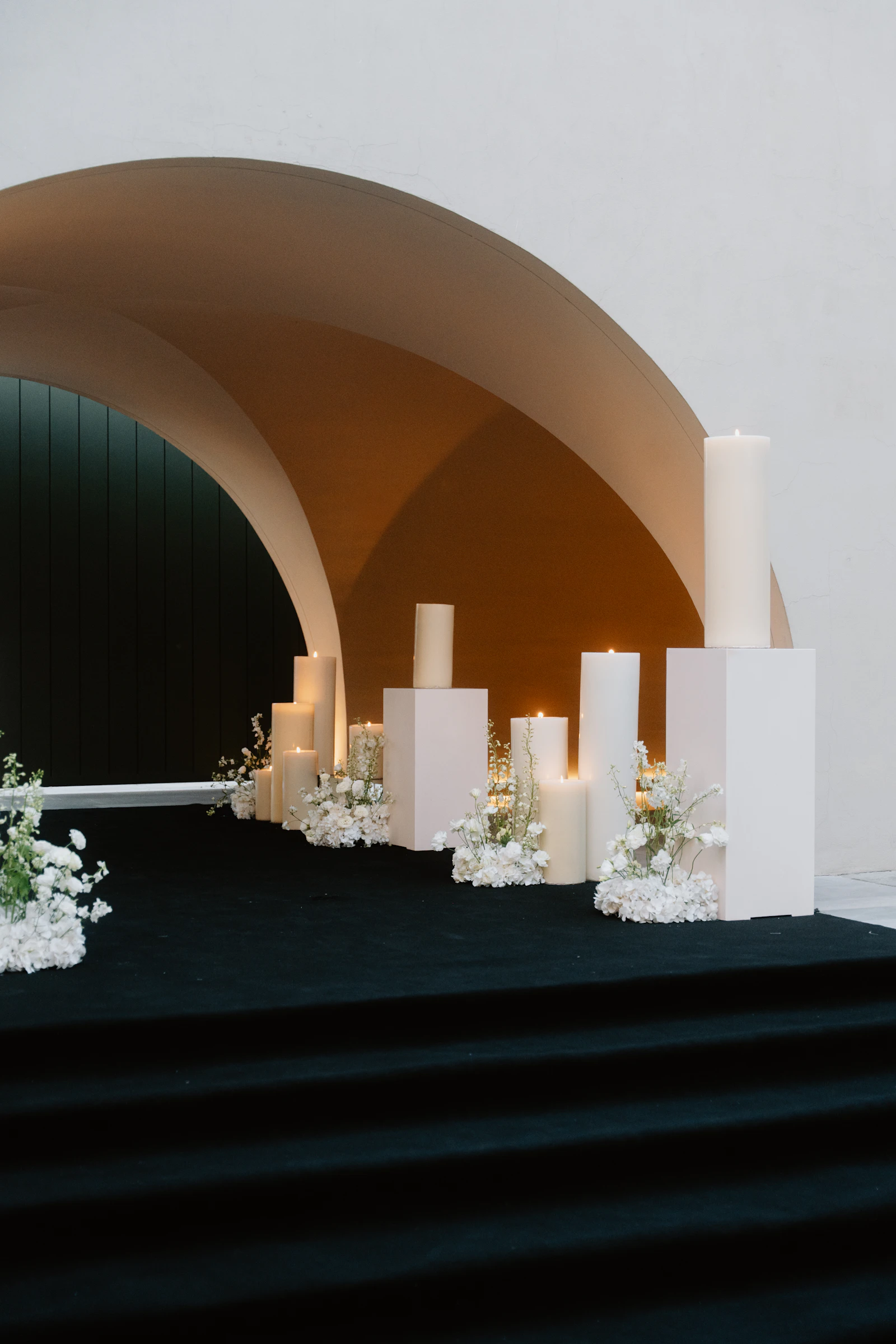 Décoration de mariage épurée avec grandes bougies et compositions florales, mobilier loué plutôt qu'acheté