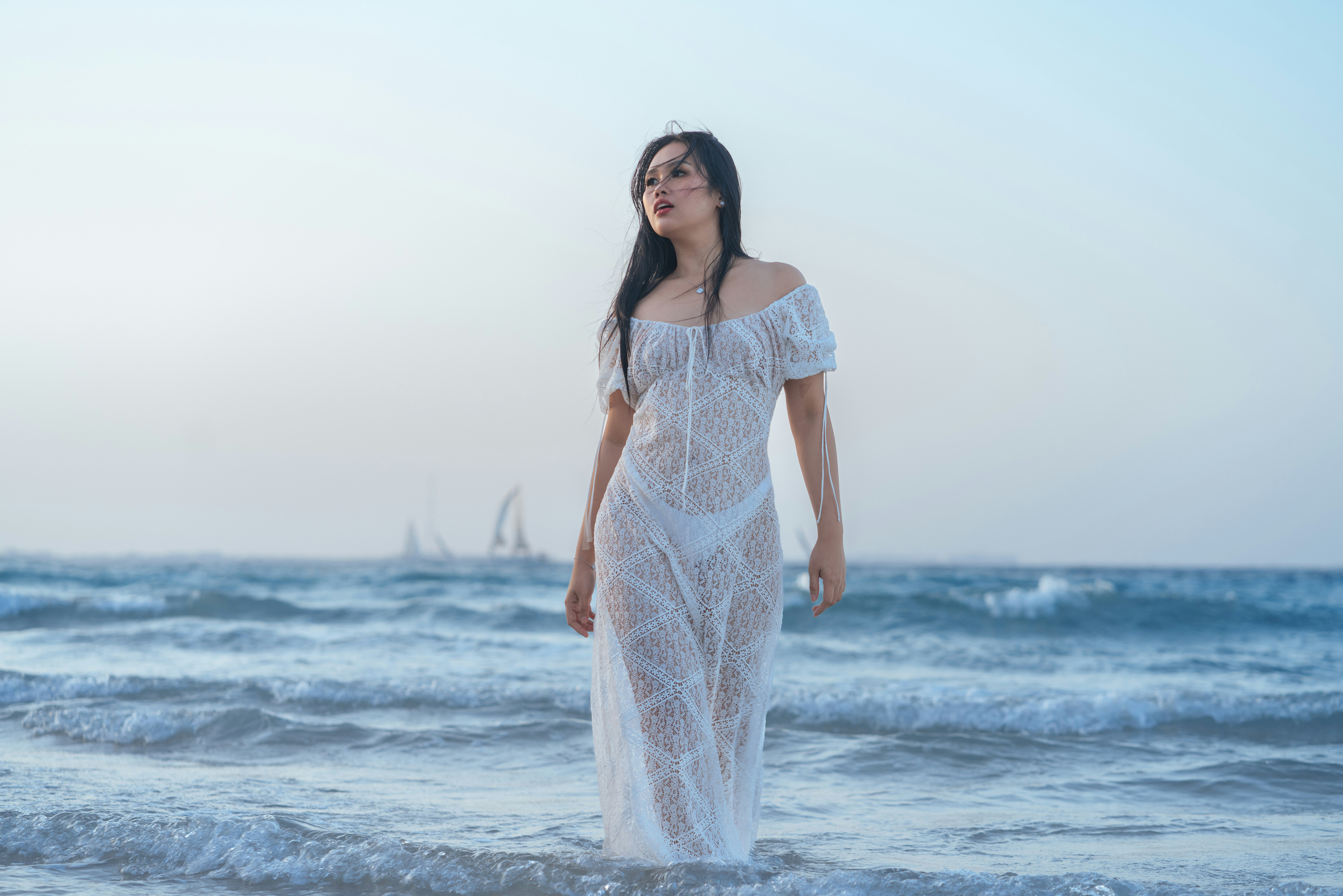Woman in white dress standing in ocean waves