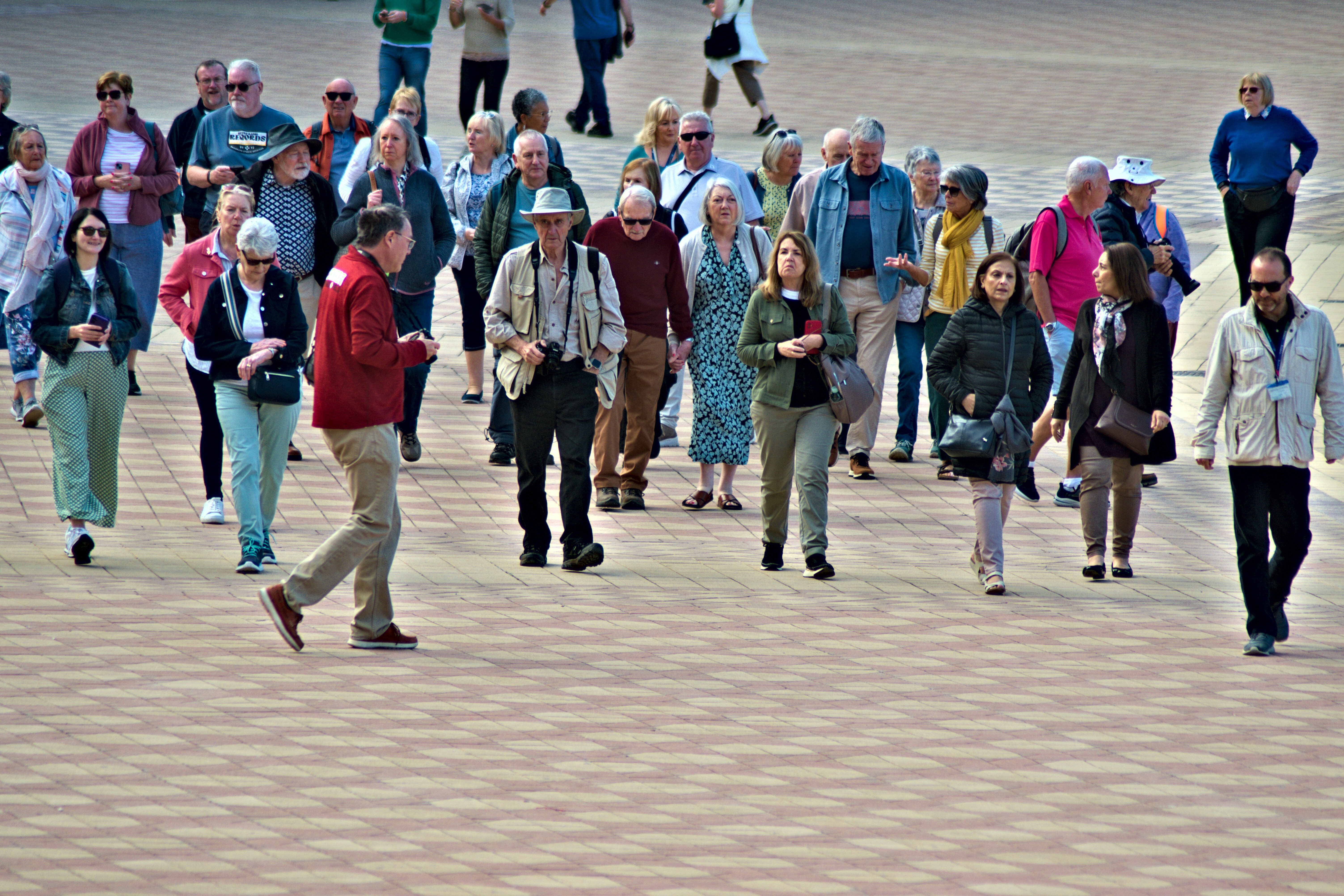 A group of people walking on a patterned pavement.