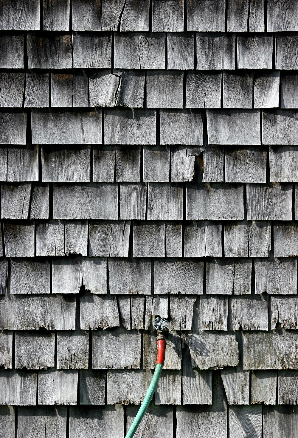 weathered wood shingle siding with a garden hose