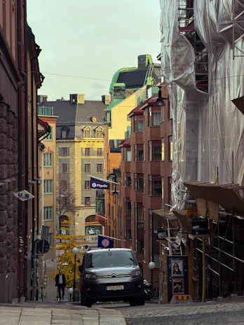 A car drives down a narrow european street.