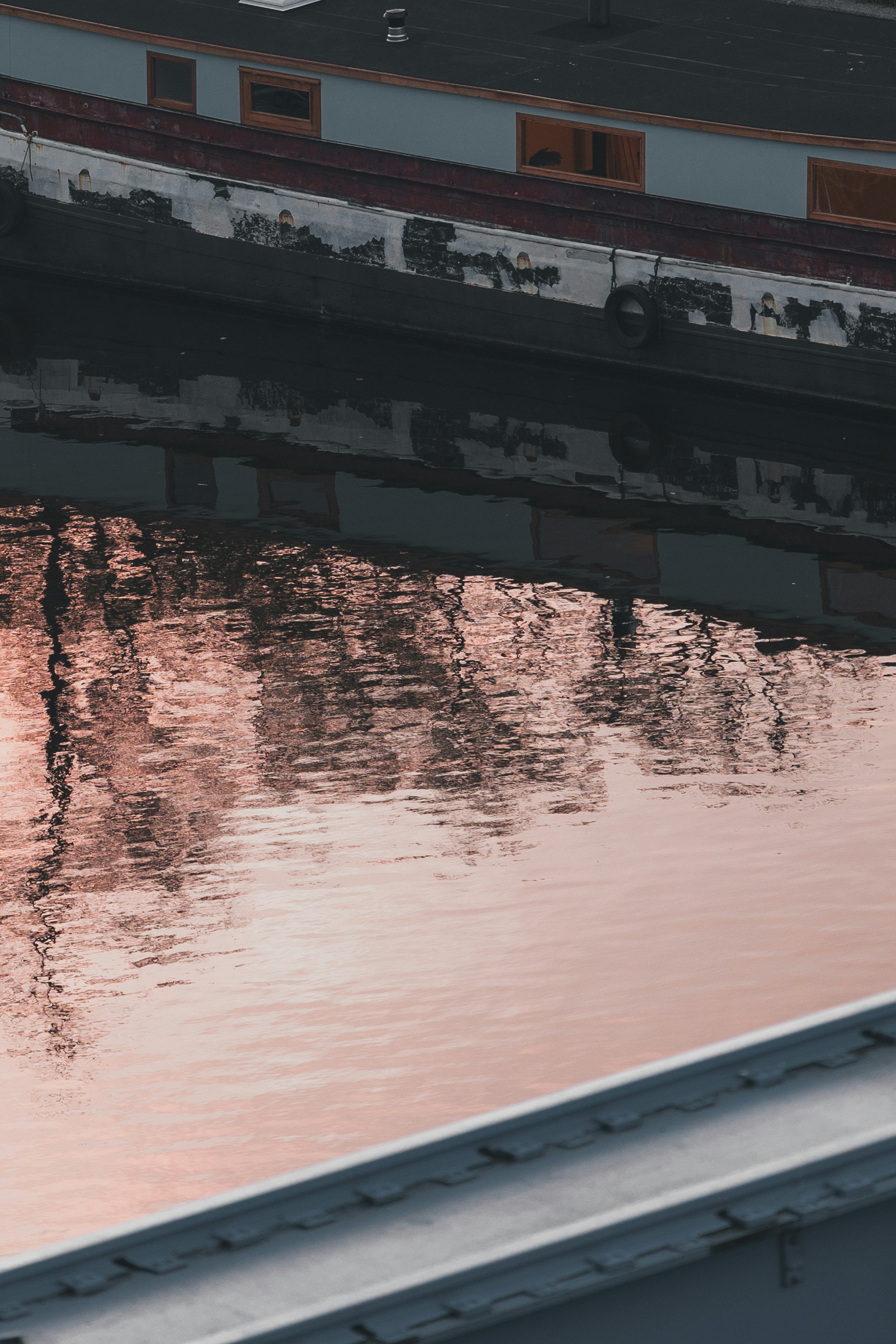 Reflection of buildings on rippling water at sunset.